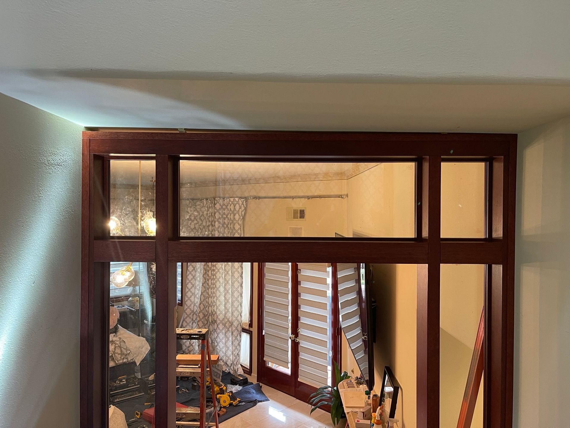 Dark wood framed doorway with glass panels, revealing room with furniture and light fixtures.