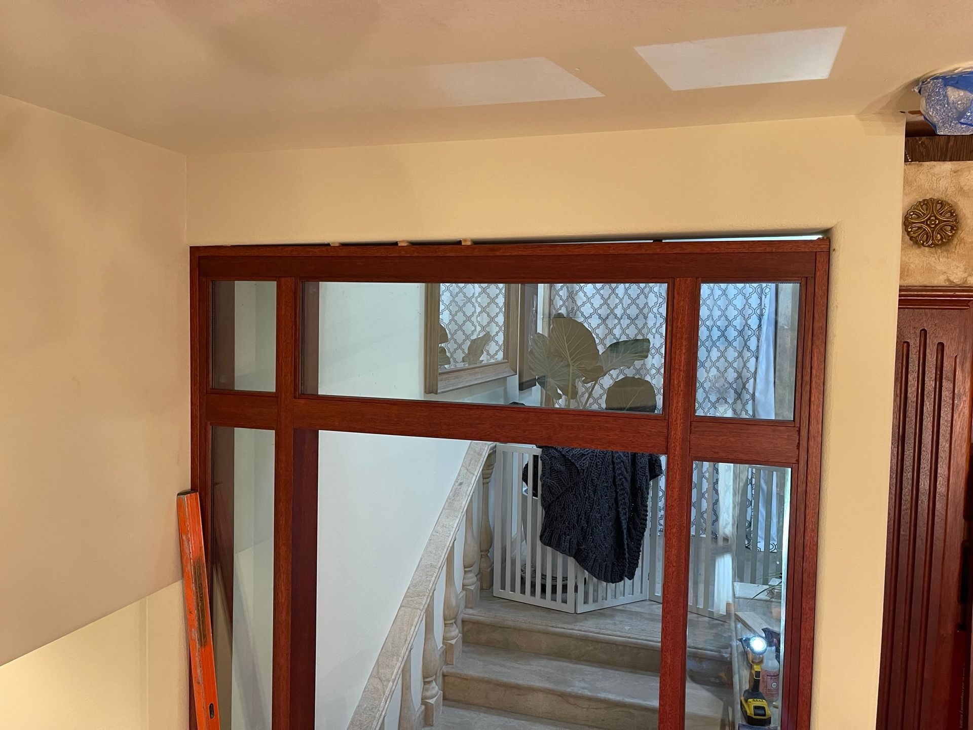 Wooden-framed doorway with glass panels, overlooking a staircase. The frame is brown, walls are beige.