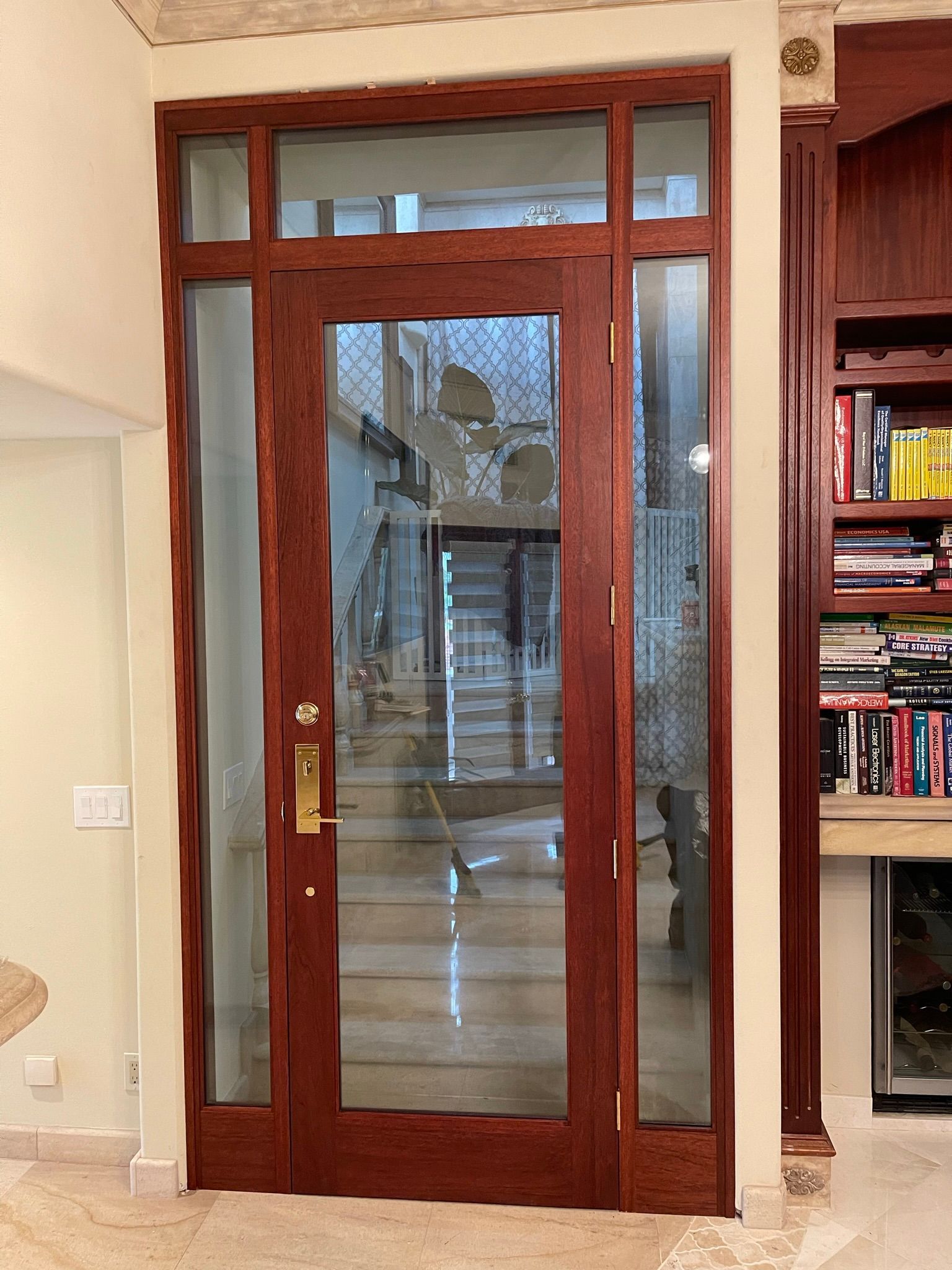 Wooden entry door with sidelights, leads to a staircase. Dark wood, clear glass, interior view.