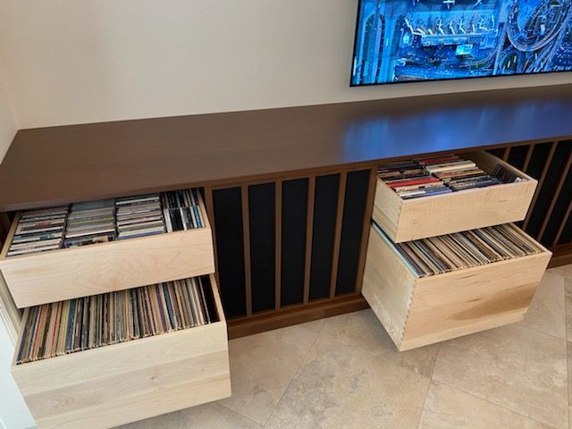 Wooden media cabinet with open drawers, displaying CDs and vinyl records.