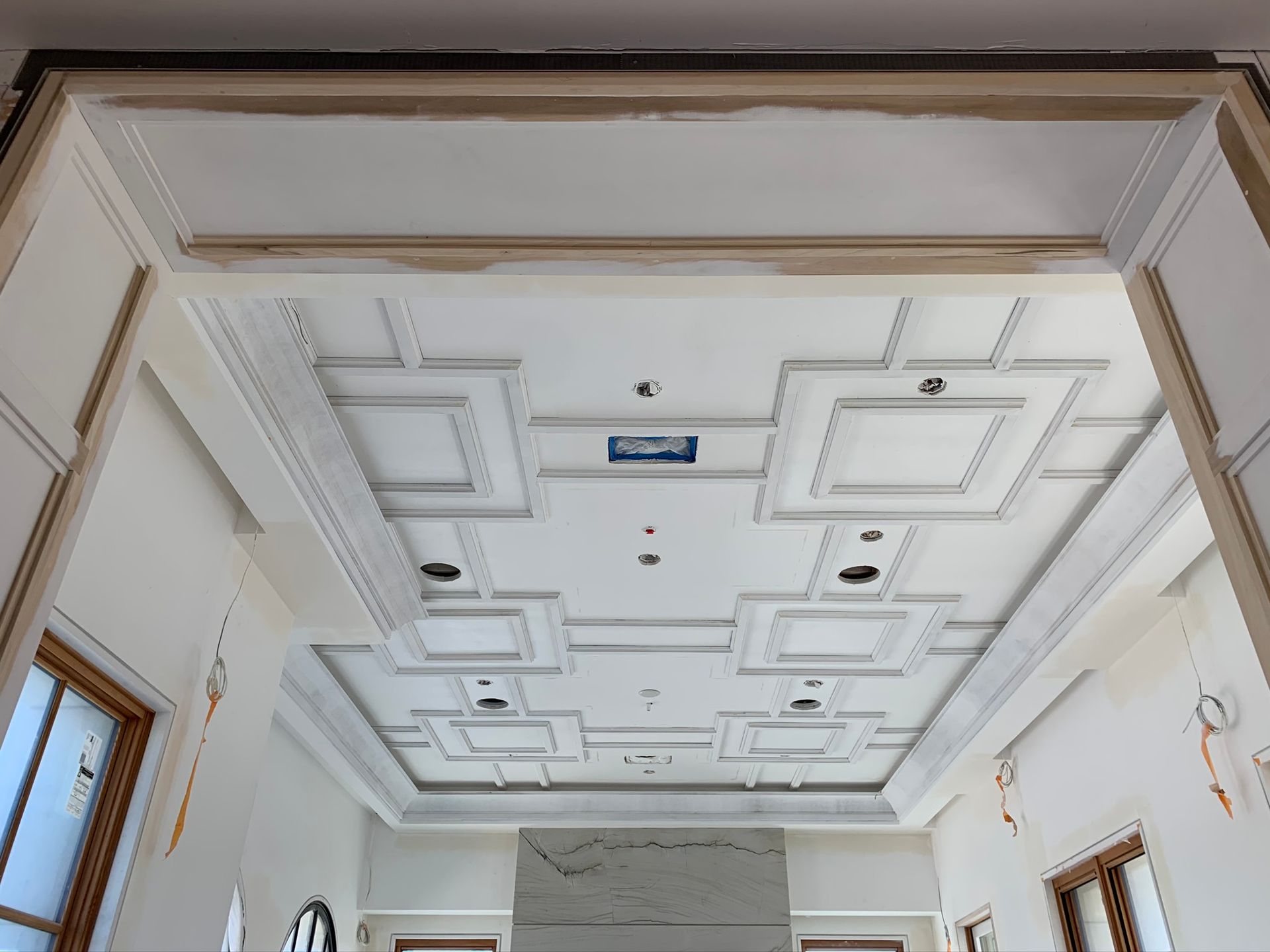 Ornate white ceiling with recessed geometric patterns, crown molding, and recessed lighting.