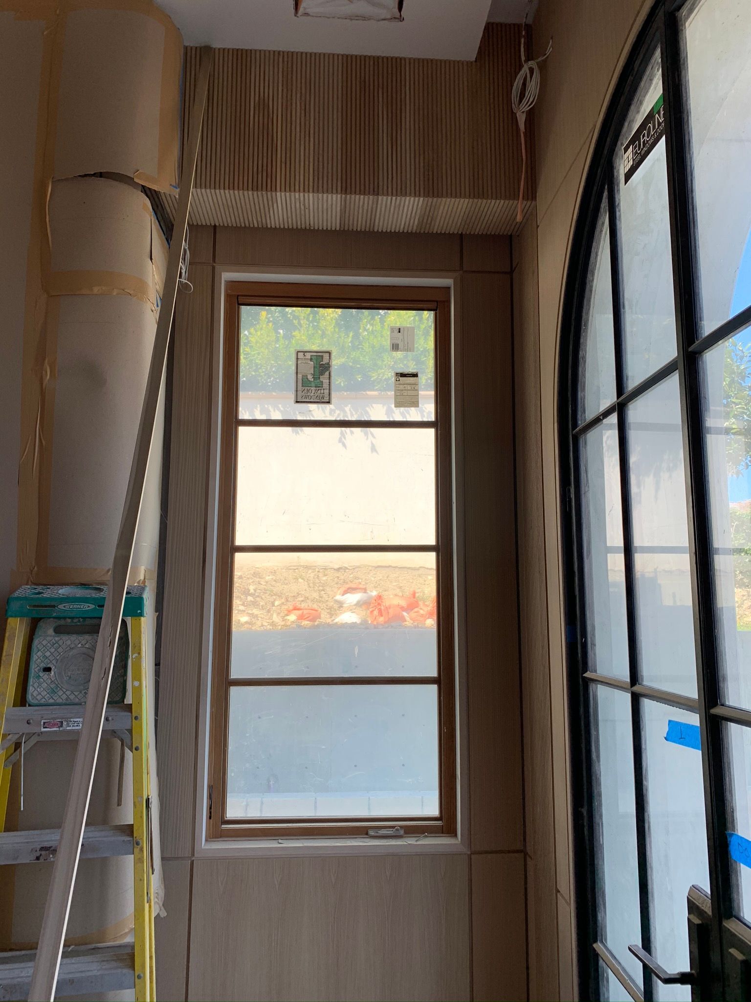 Interior doorway with window and arched black door. Construction in progress.