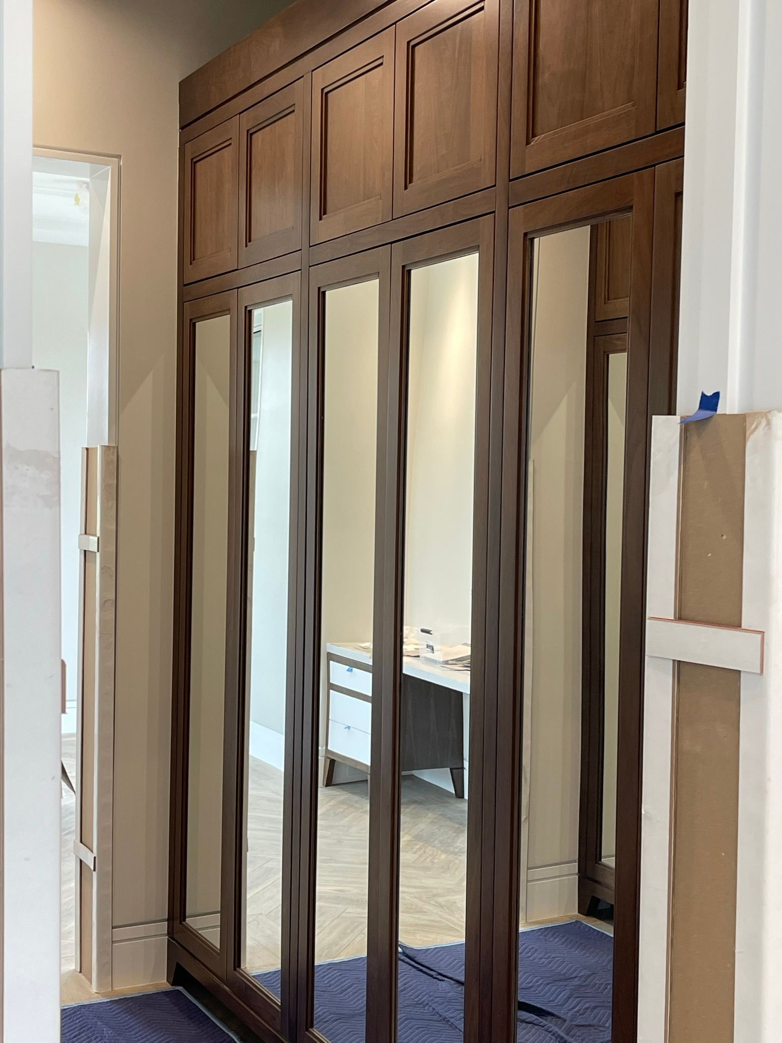 Wooden closet doors with wavy mirror panels. Inset paneling and trim, a room reflection.