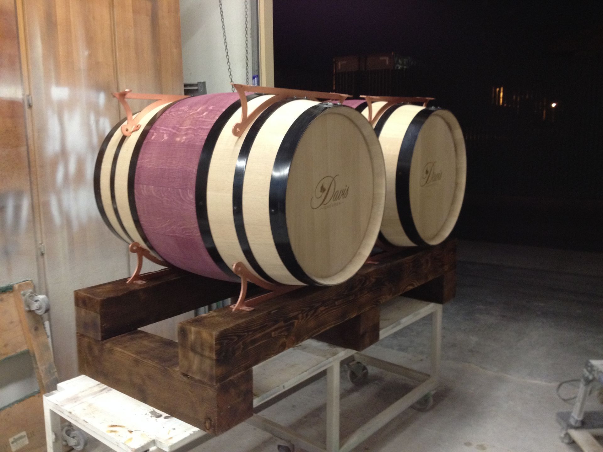 Two wooden wine barrels on a dark stained wooden base, with copper accents.
