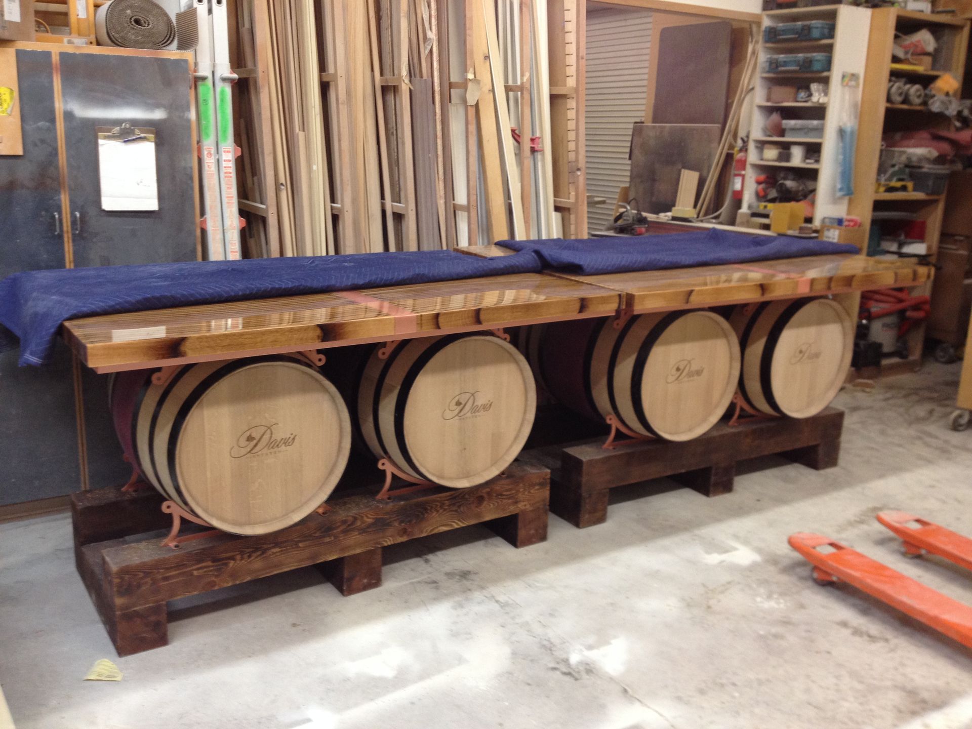 Two wooden barrel tables with blue padding, in a workshop.