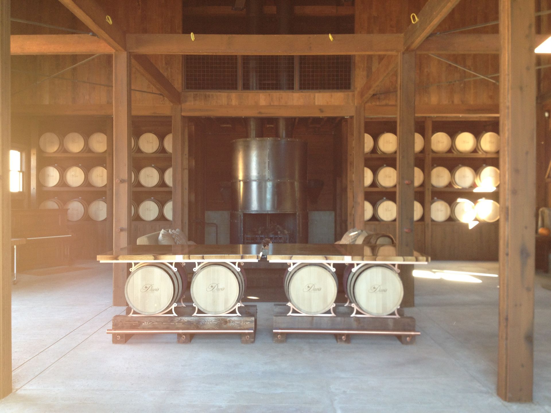 Interior of a distillery with barrels on display shelves and a central still.