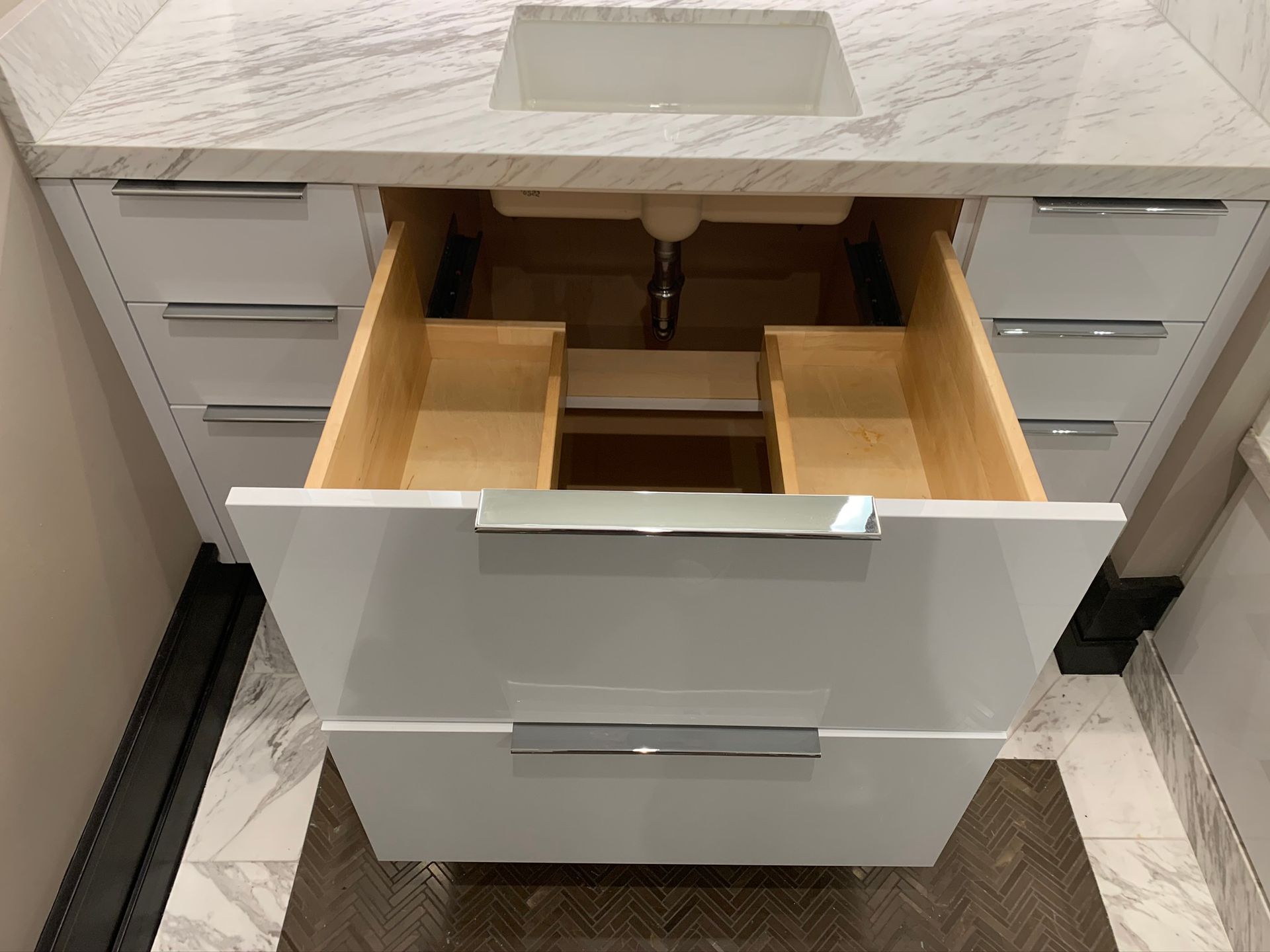 White bathroom vanity with open drawer; sink and countertop visible.
