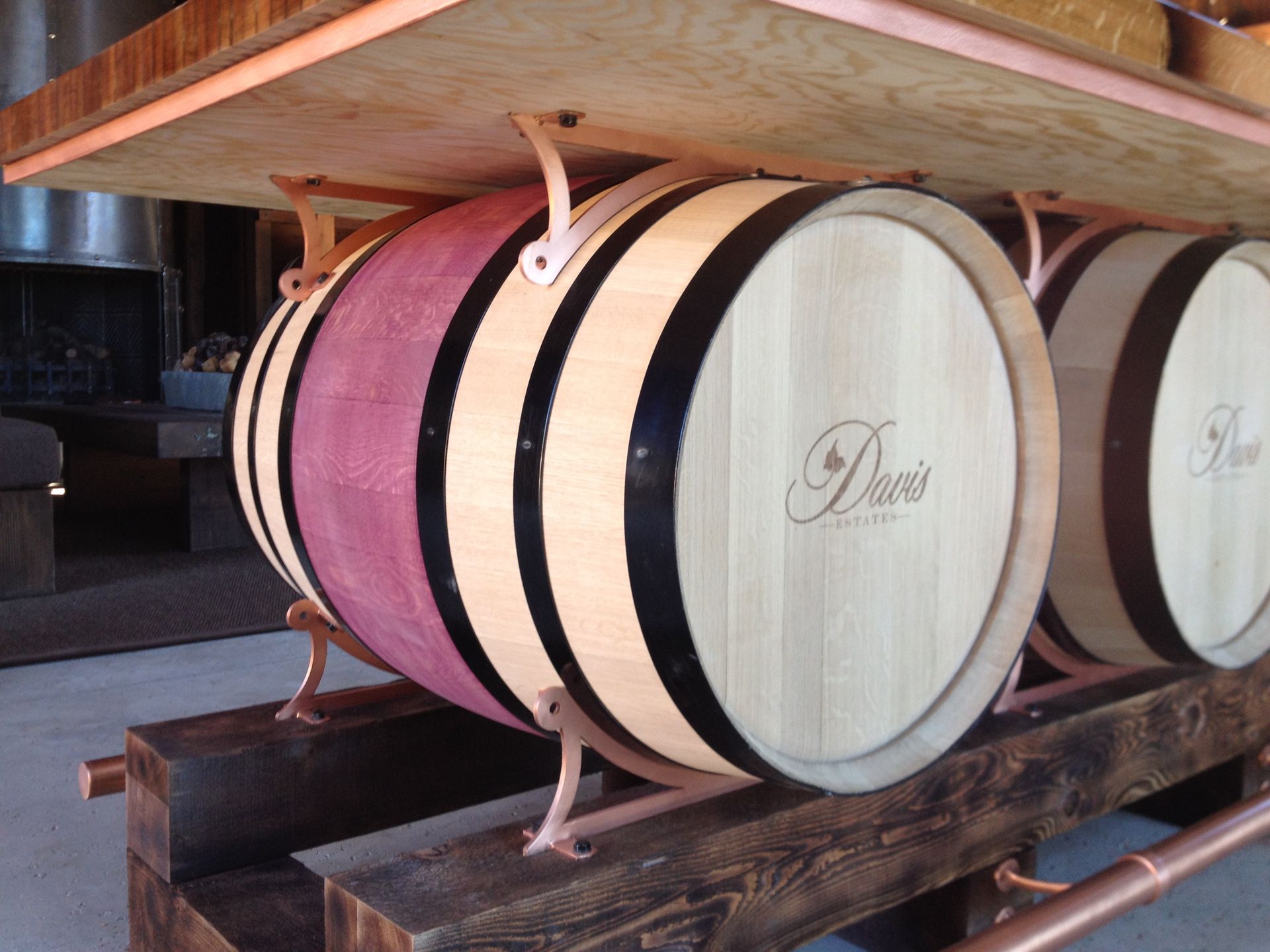 Wine barrels support a wooden table; copper hardware and trim details.