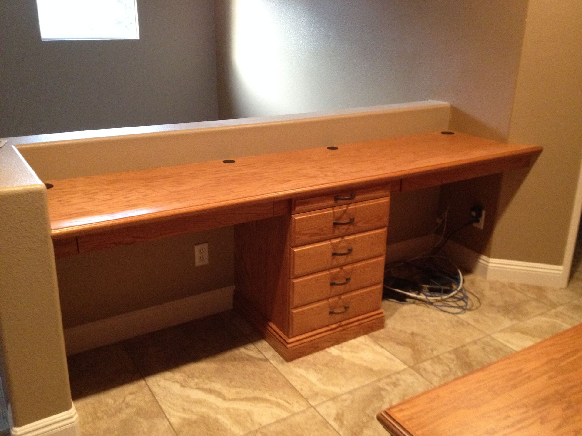 Built-in wooden desk with drawers, in a basement. Brown and tan colors.