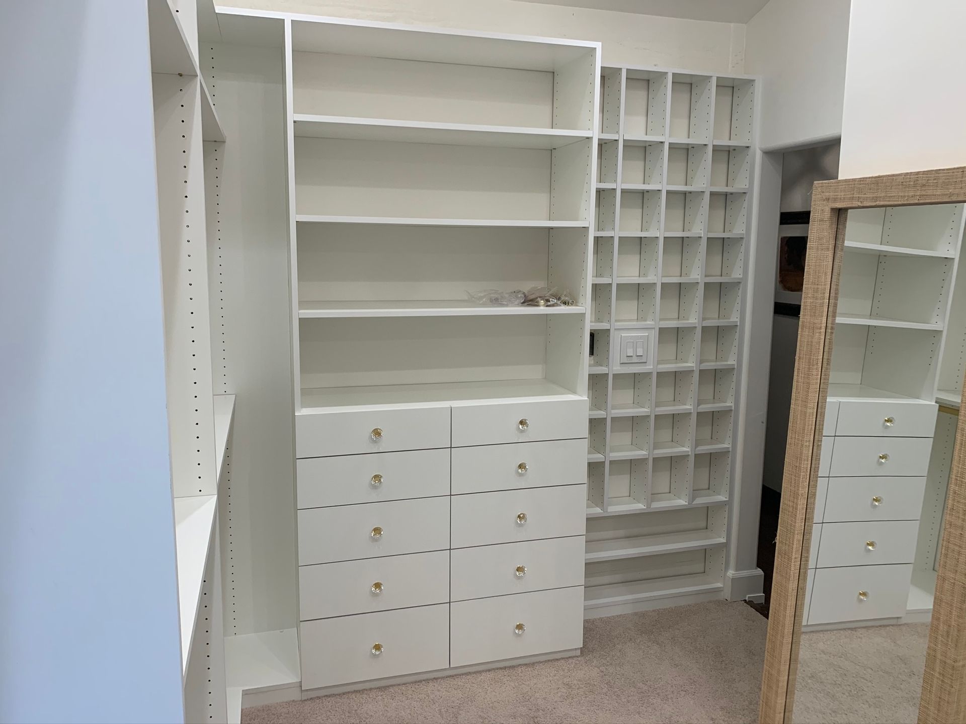 White custom closet with shelves and drawers. A full-length mirror is on the right side.
