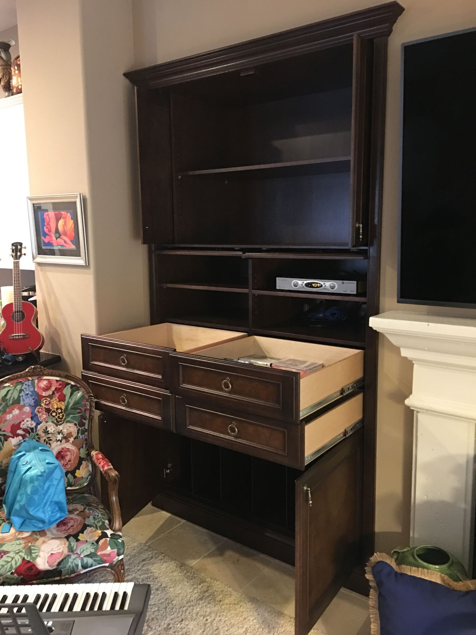 Dark wood entertainment cabinet with open drawers and doors.