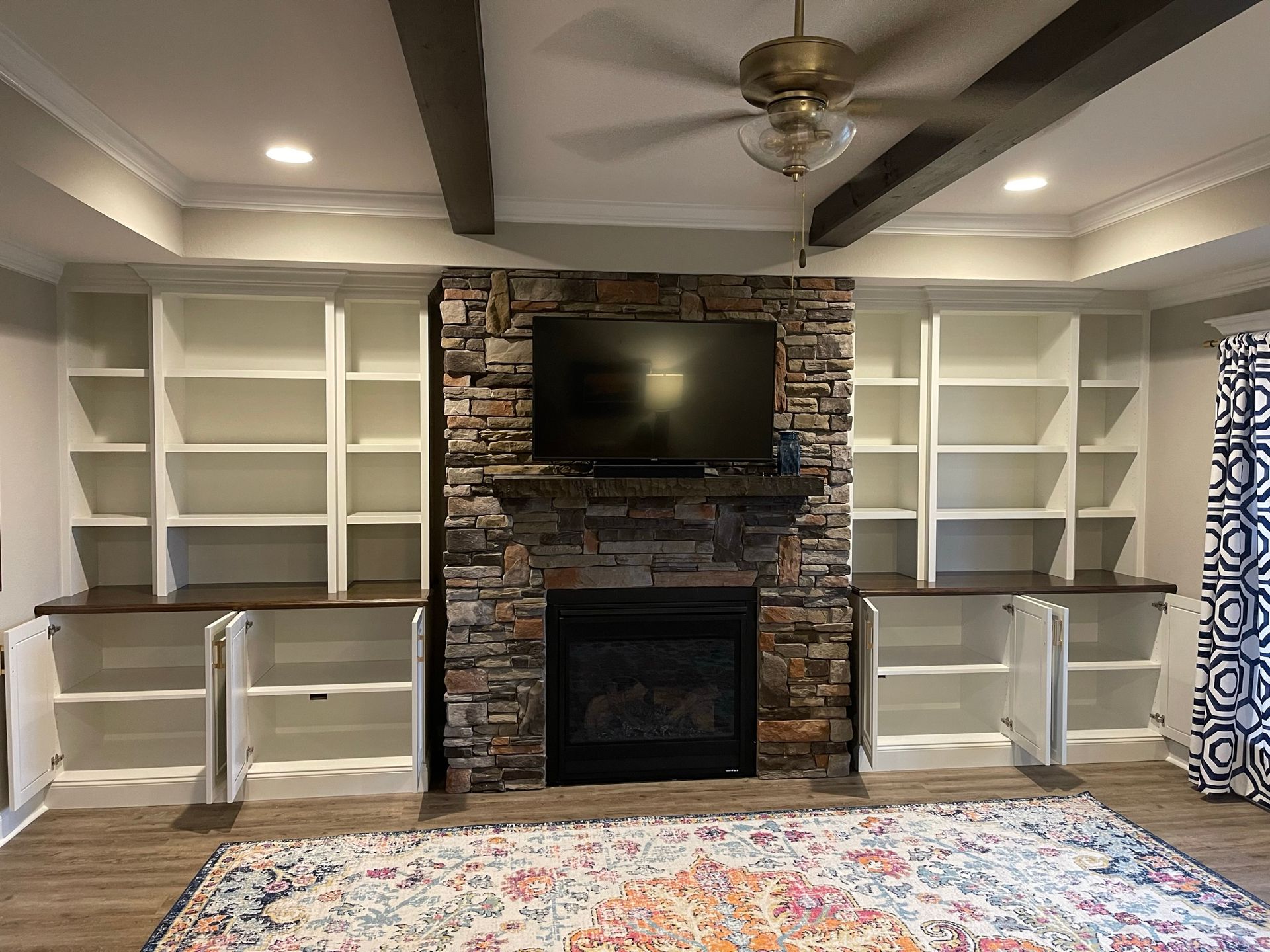 Built-in bookshelves flank a stone fireplace with a TV above. 