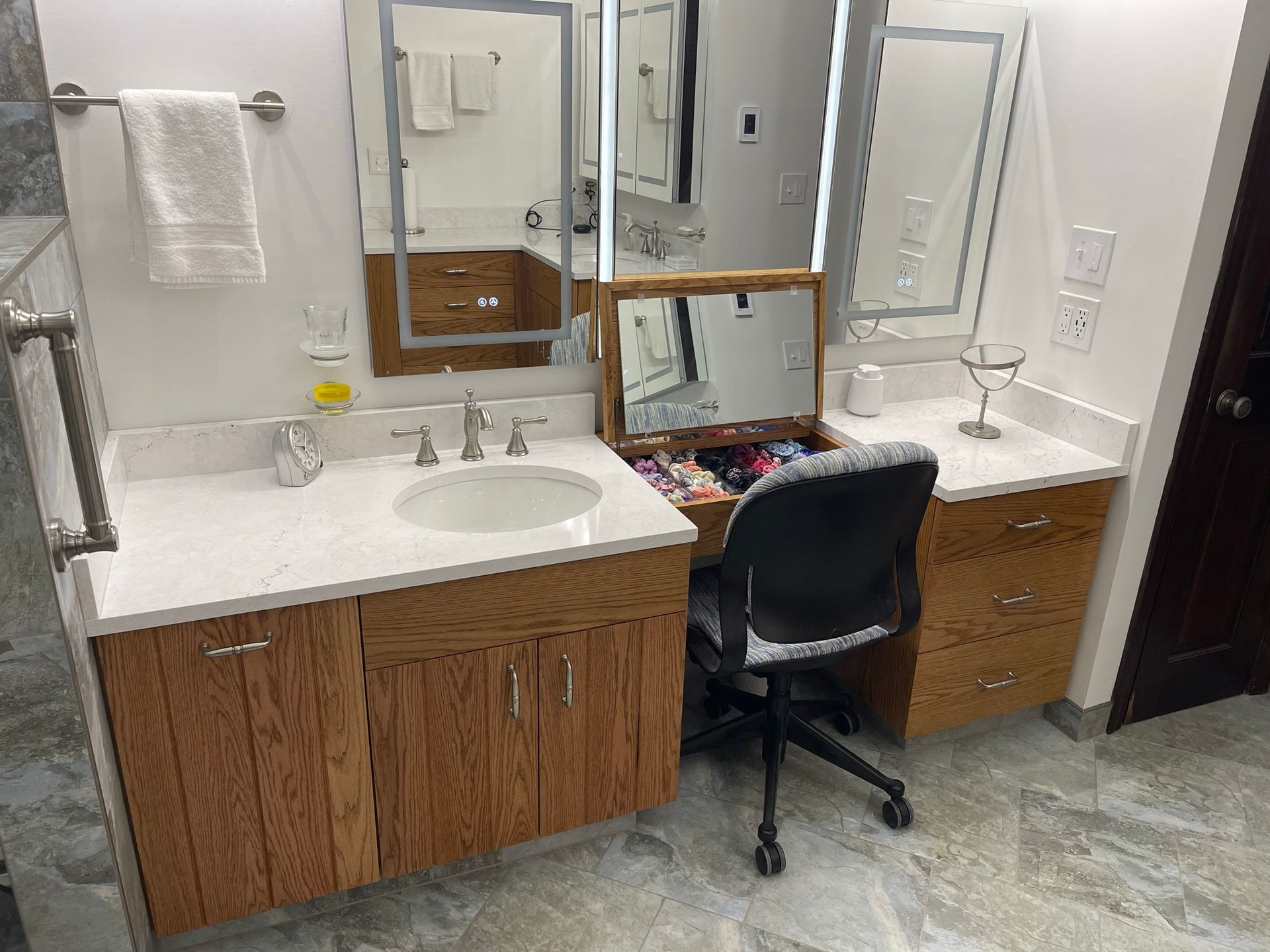 Bathroom vanity with countertop, sink, mirrors, and a seated desk.
