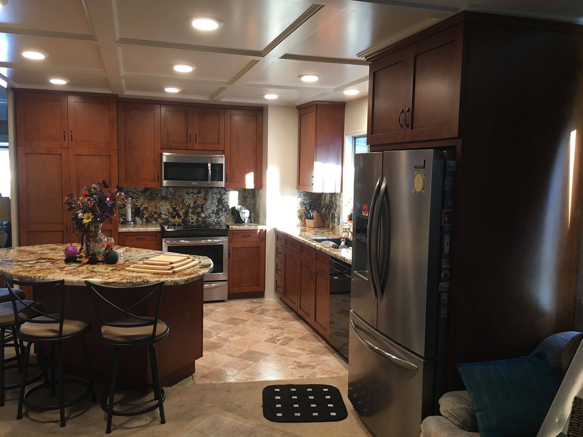 A kitchen with dark wood cabinets, stainless steel appliances, and a granite countertop island.