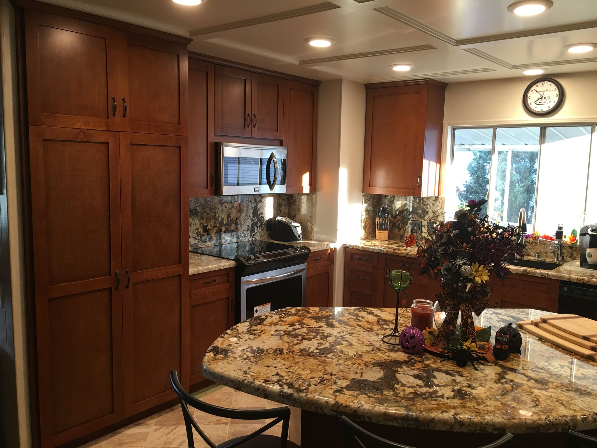 Kitchen with wood cabinets, granite countertops, and an island. Stainless steel appliances and recessed lighting.