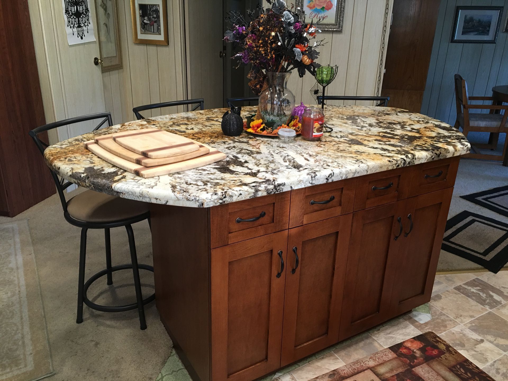 Kitchen island with a granite countertop, wooden cabinets, and bar stools.