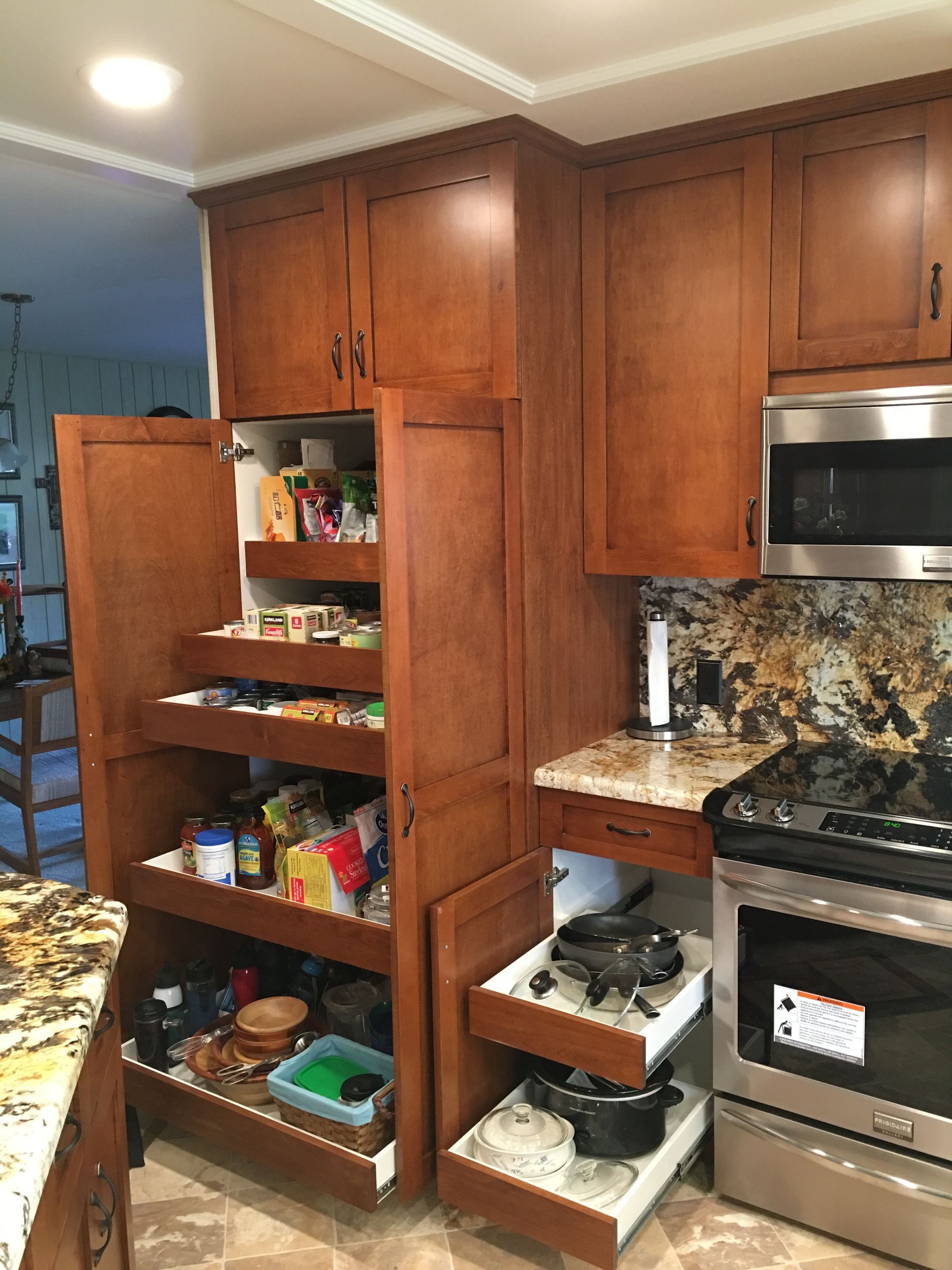 Kitchen with open pantry and pull-out drawers; wooden cabinets, granite countertops, stainless steel appliances.