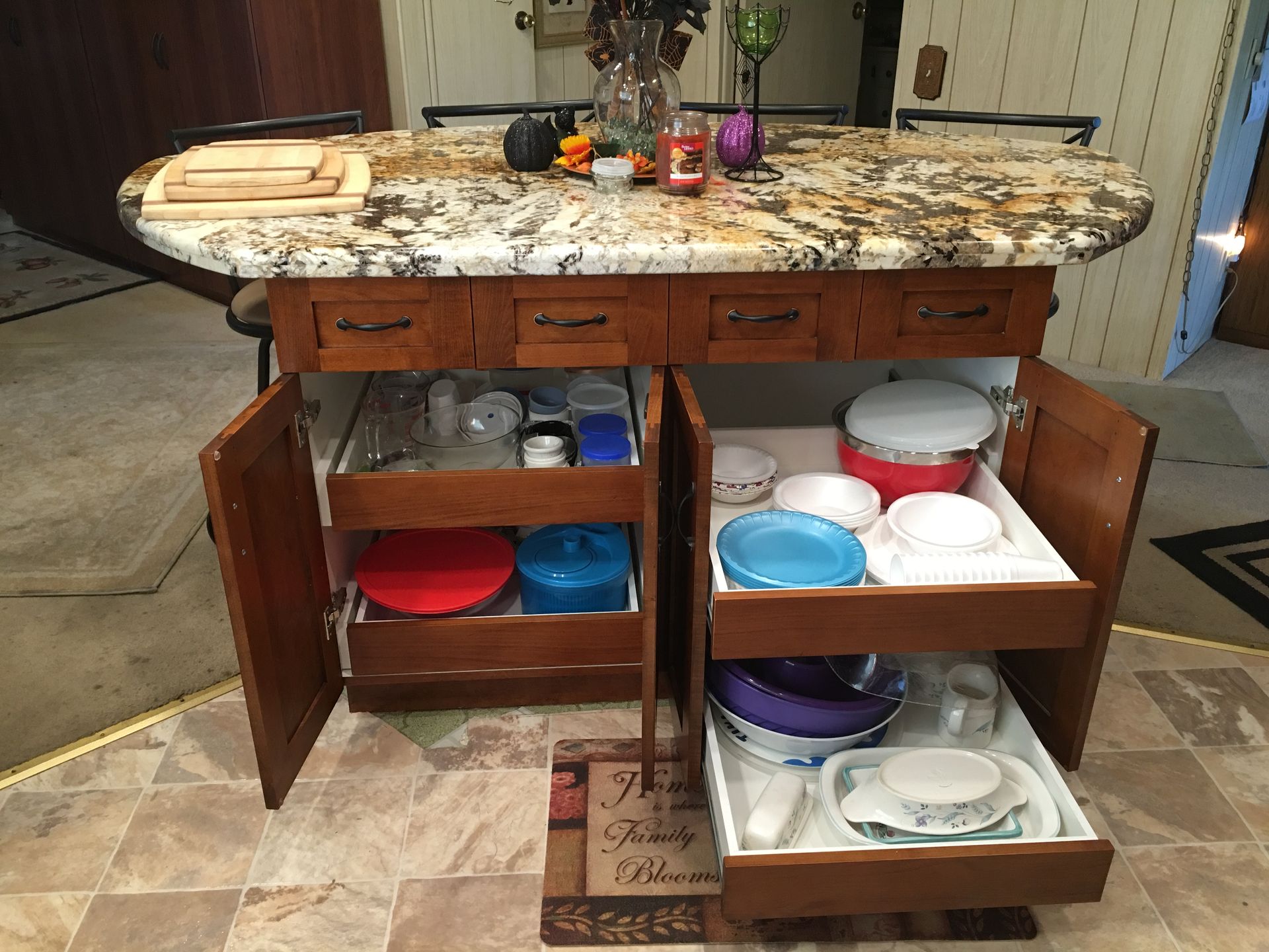 Kitchen island with granite countertop, cabinets open to reveal dish storage.