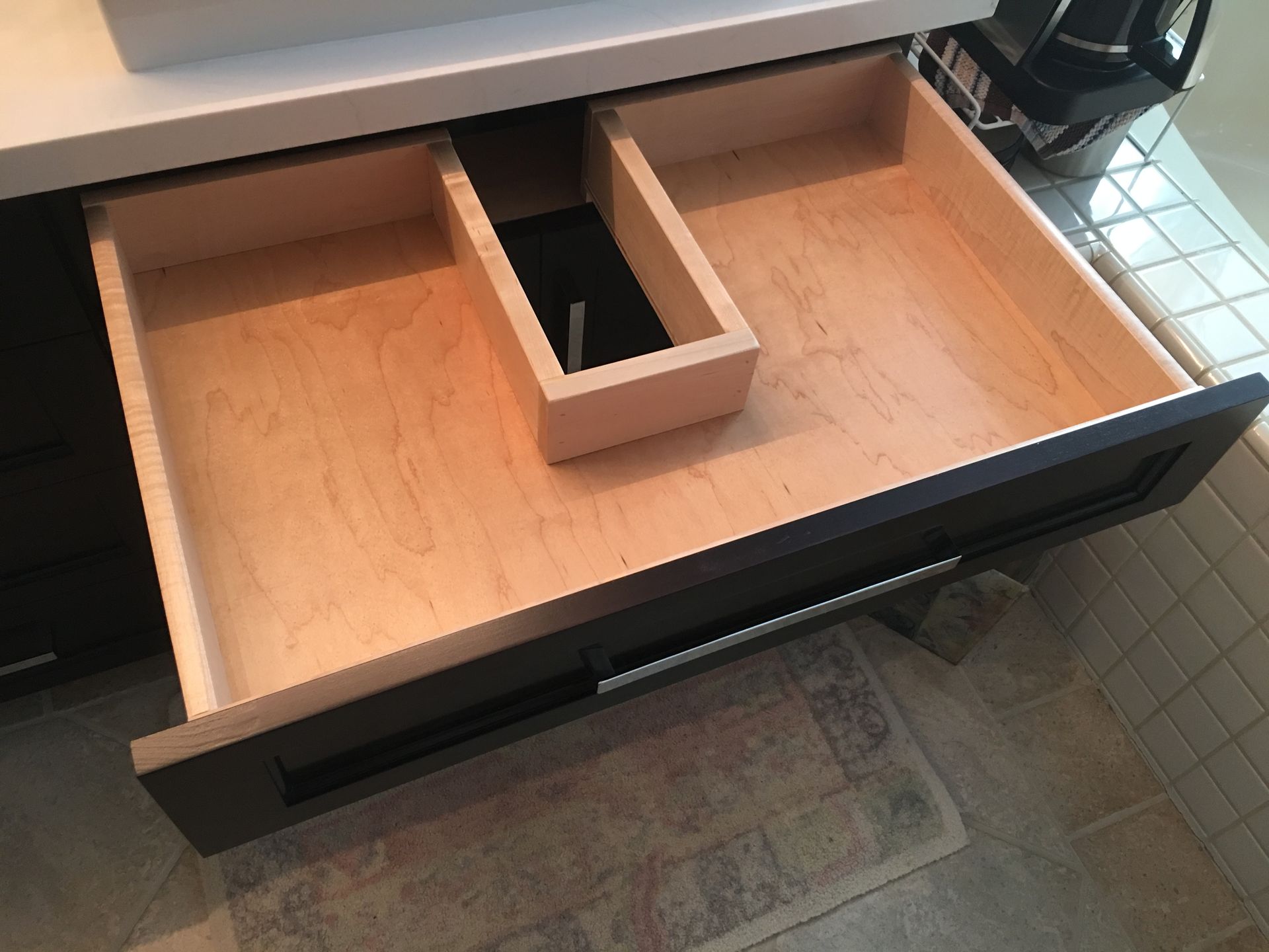 Open dark brown bathroom drawer with wooden dividers.