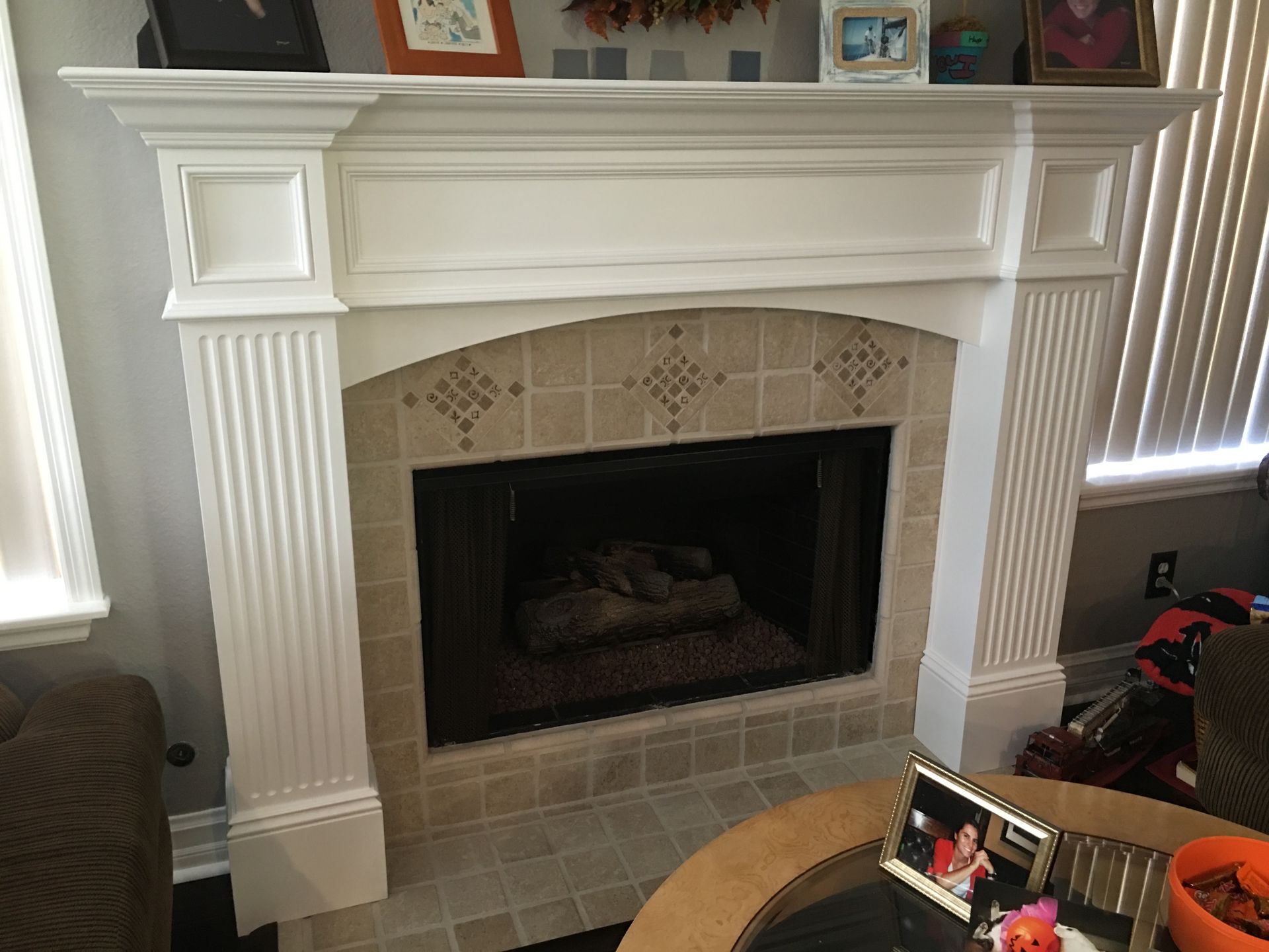 White fireplace with fluted columns, beige tile surround, and a dark interior.