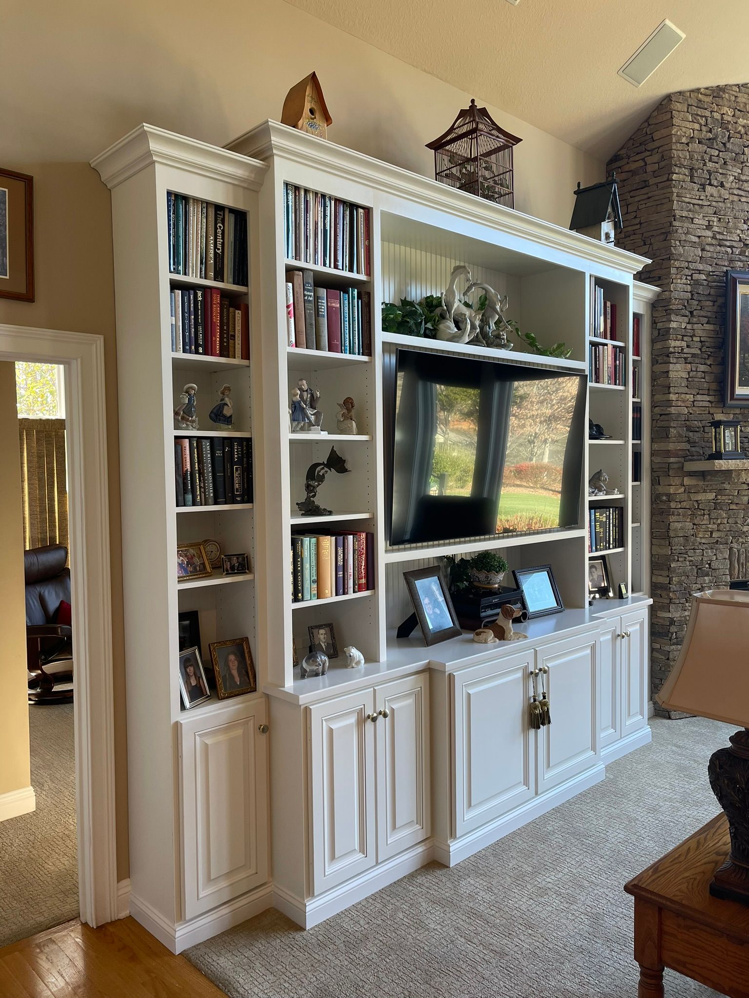 White built-in entertainment center and bookshelves, with books, a TV, and decorative items.