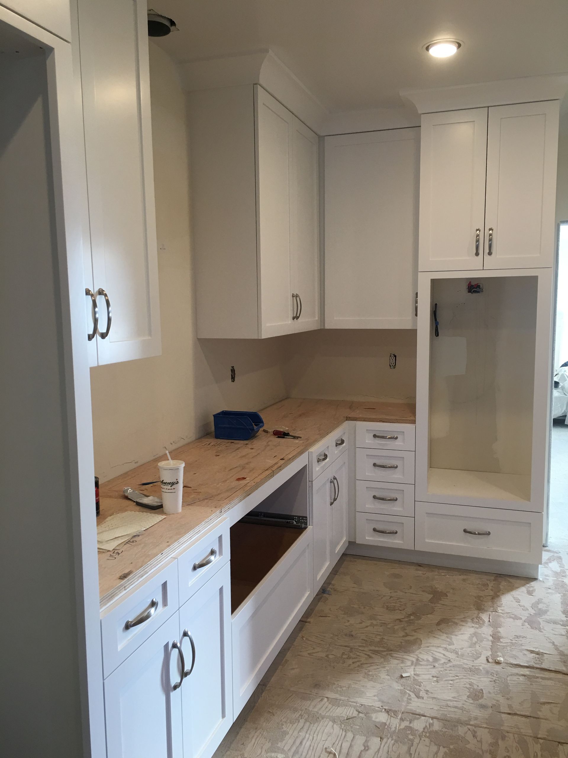 White kitchen cabinets under construction. Brown countertop. New construction.
