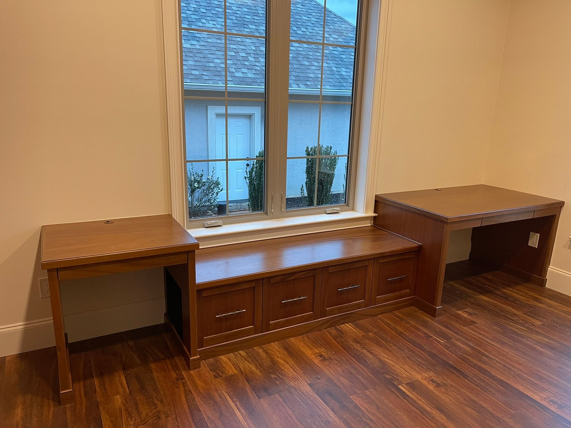 Wooden desks and storage bench built into a window alcove; dark wood floor.