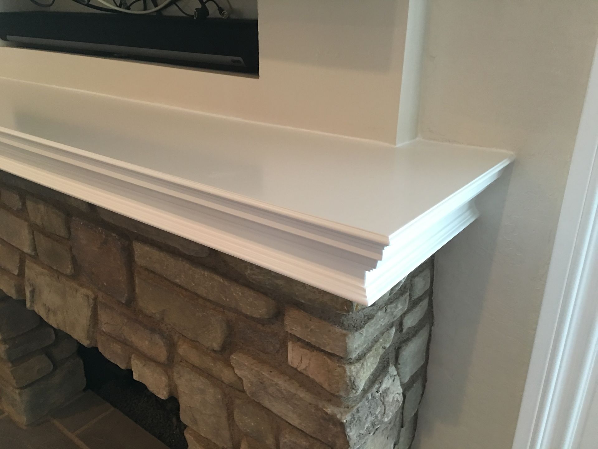 Fireplace with stone facade, white mantel, and built-in television above.