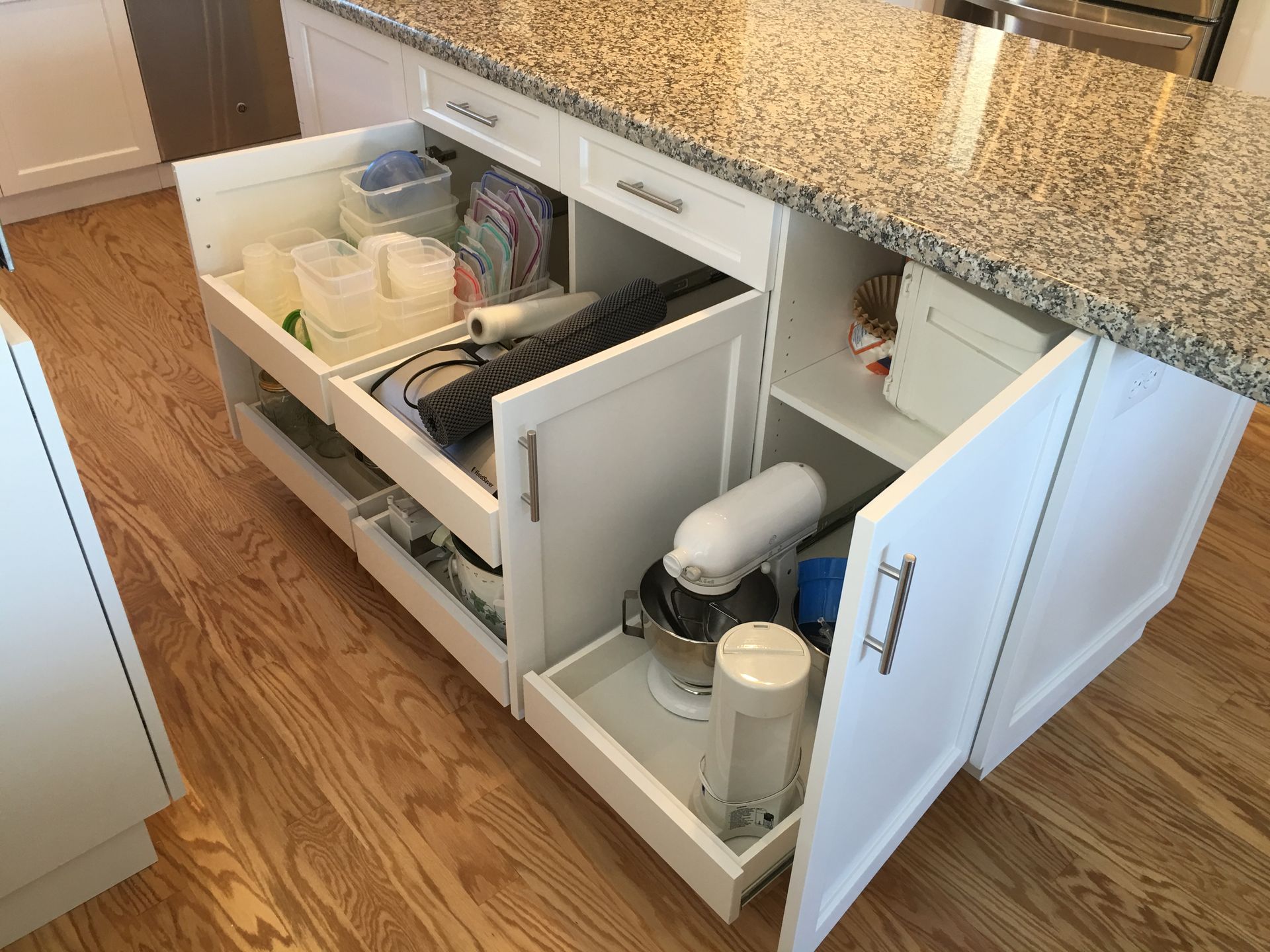 White kitchen island with open cabinets revealing storage for kitchen appliances and supplies.