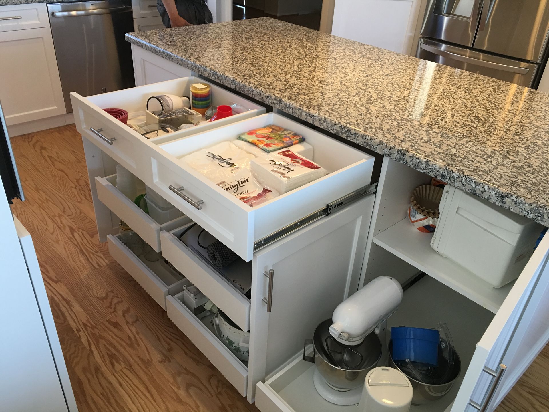 Kitchen island with granite countertop, several open drawers revealing storage.