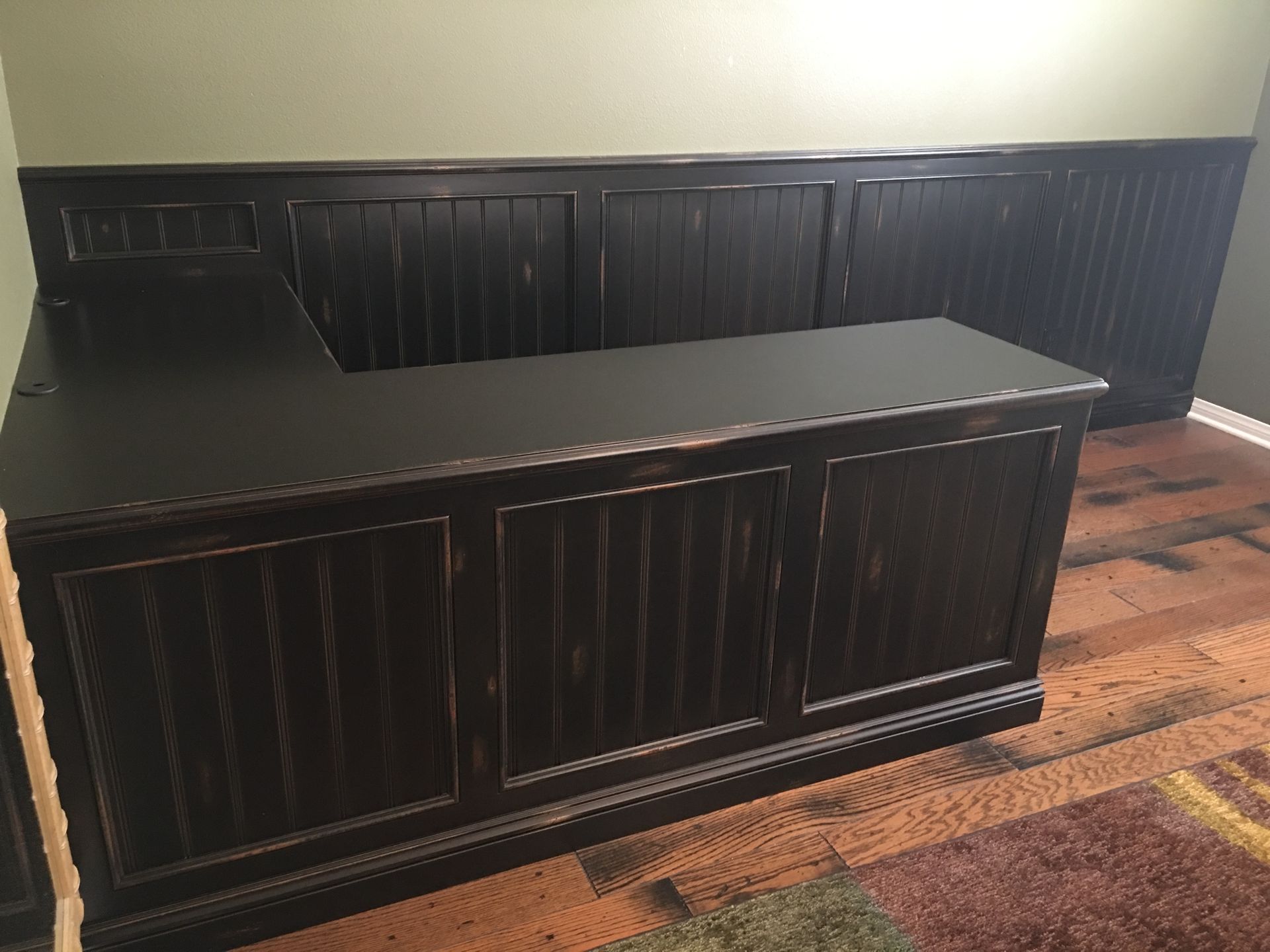 Dark brown wooden desk with vertical paneling, against a wall with matching wainscoting.
