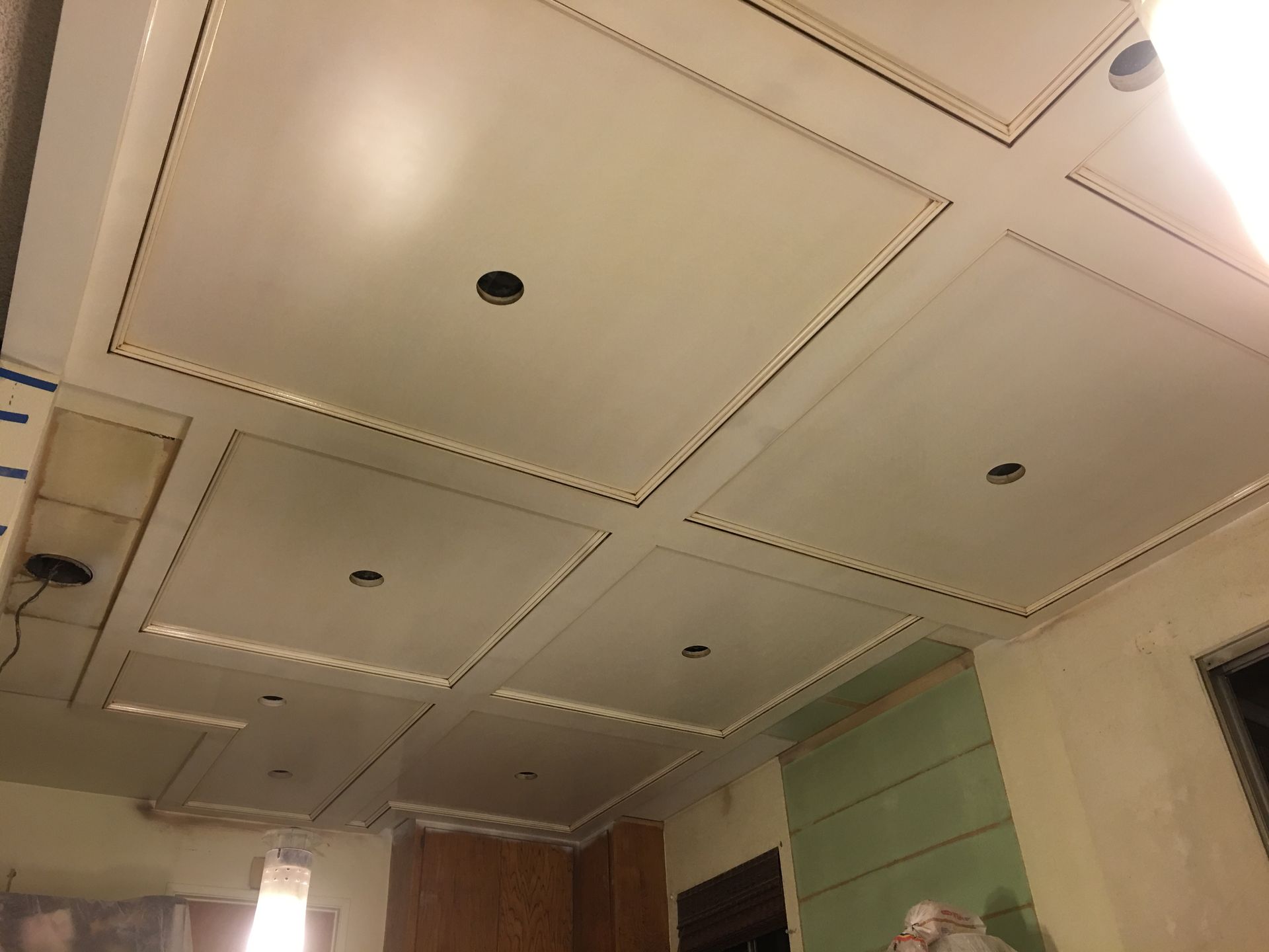 White ceiling with recessed panels, dotted border lights, and recessed lighting fixtures.