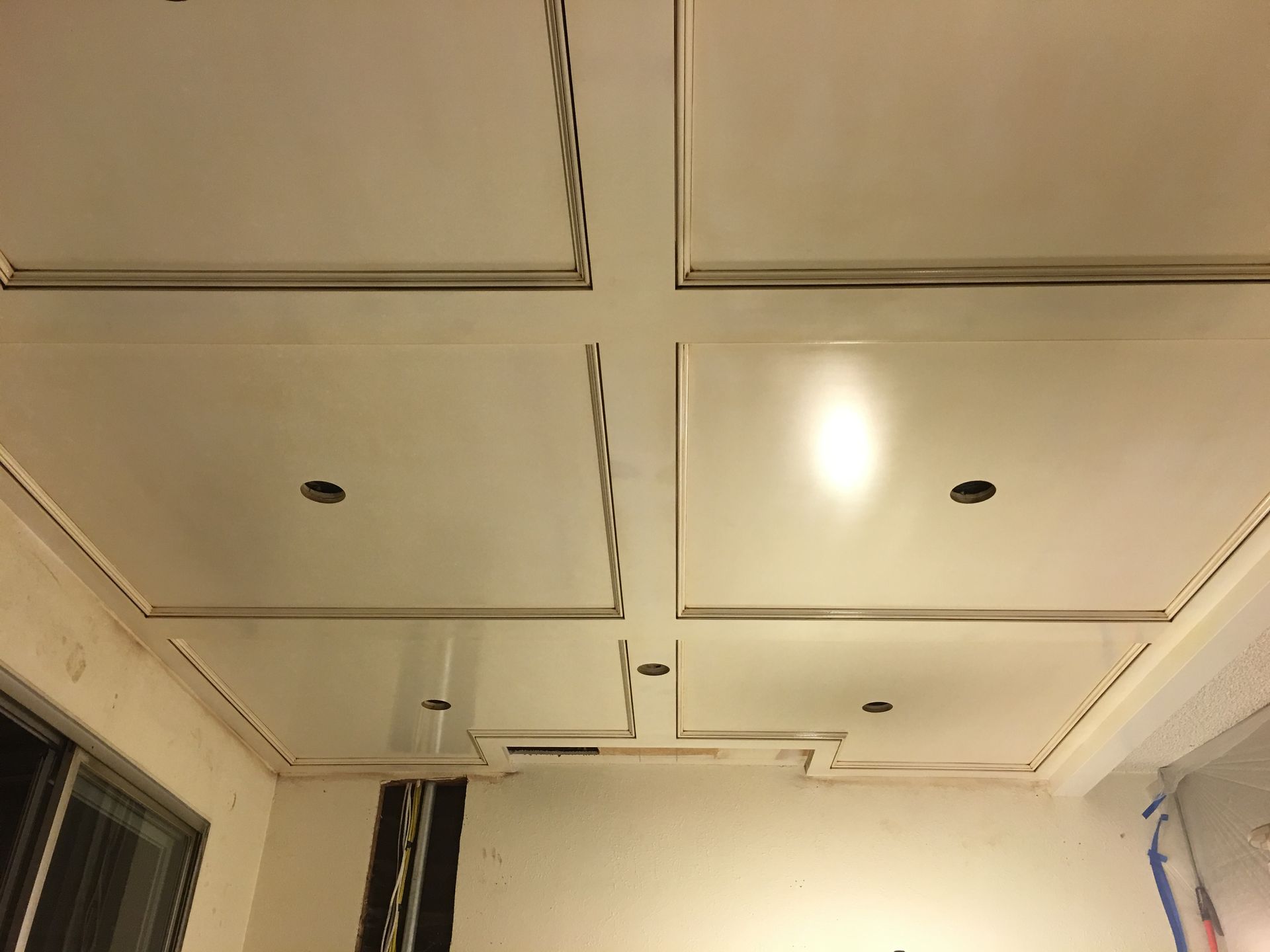 White coffered ceiling with recessed squares and recessed lighting holes.