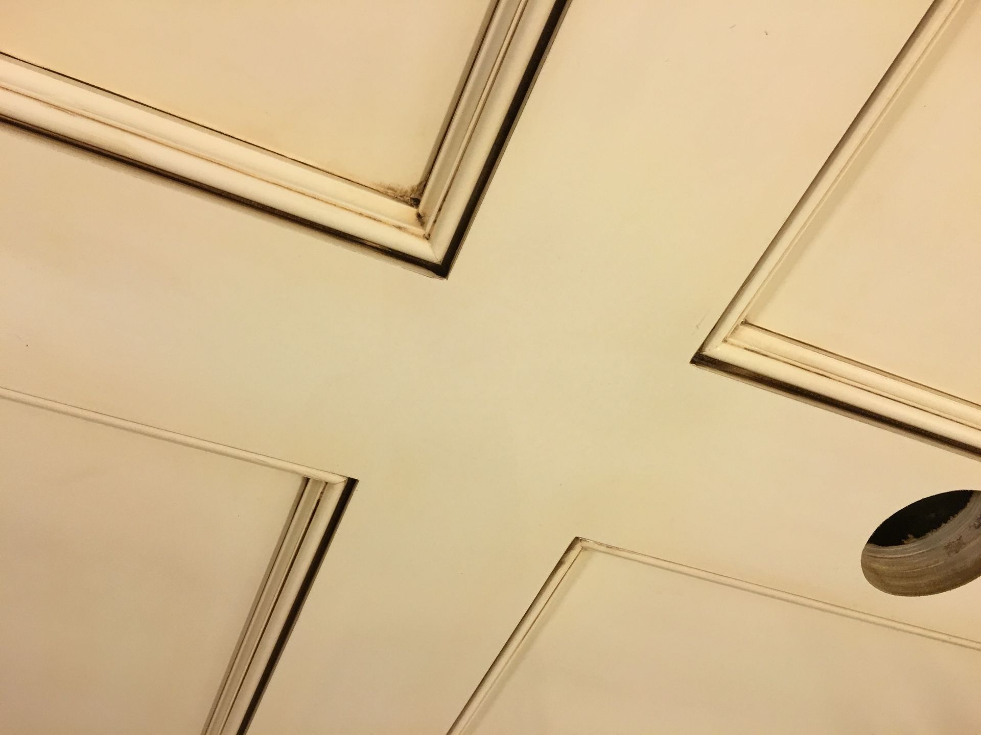 Cream-colored door panel with a cross-shaped design and a circular hole in the lower right corner.