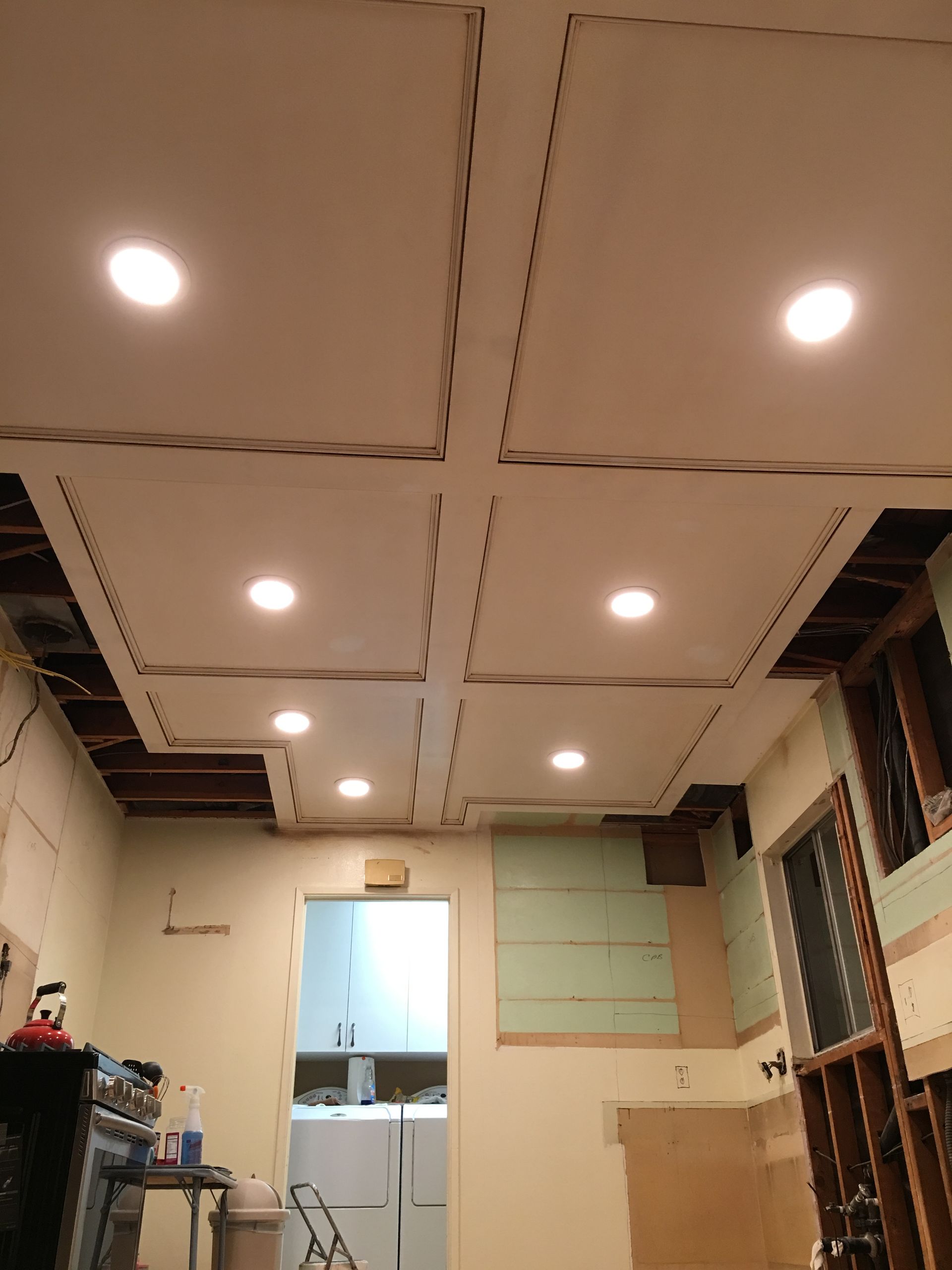 Ceiling with recessed lights in a room under construction; drywall panels and exposed framing.