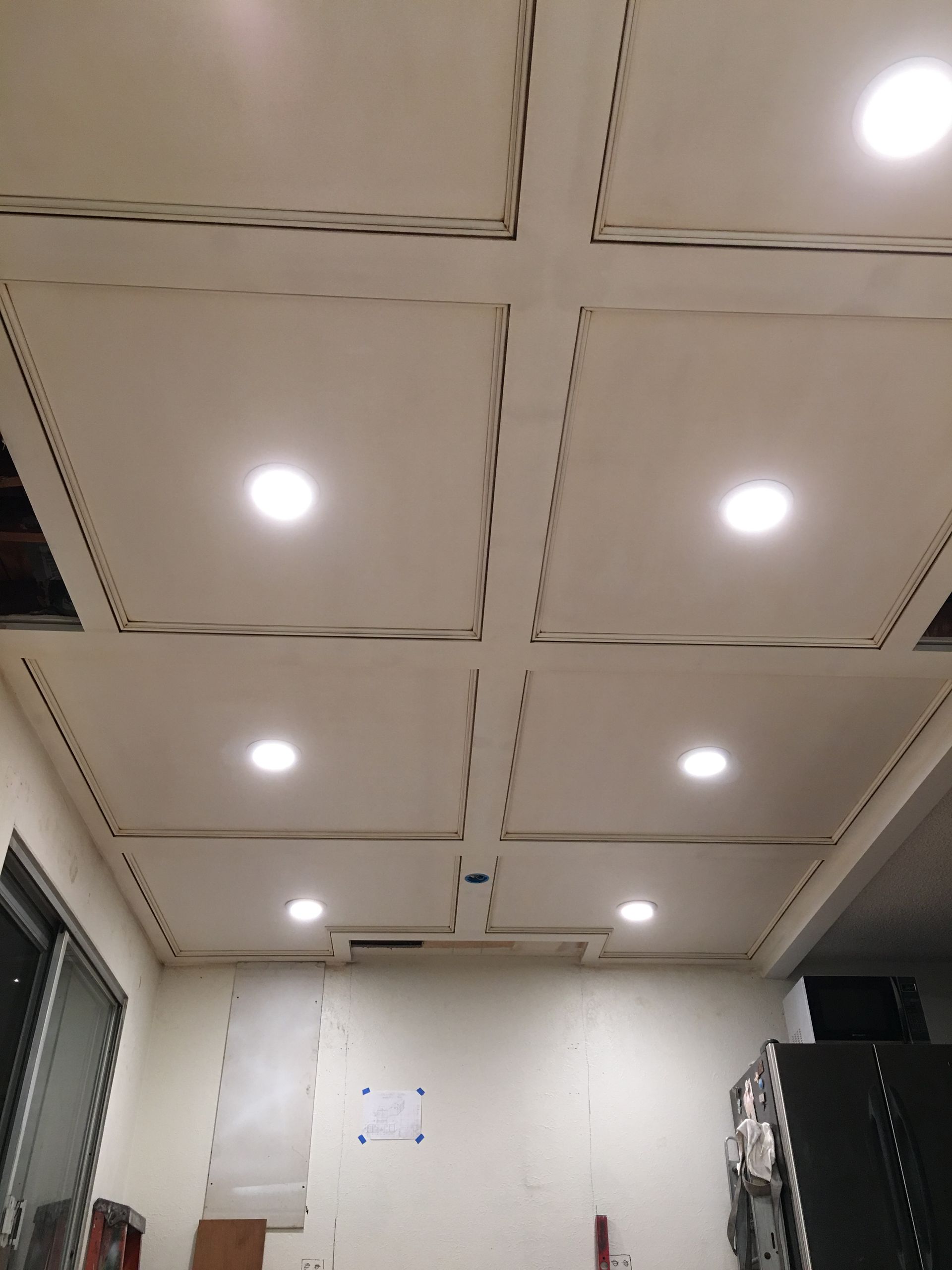 White ceiling with recessed lighting and square panels. Room with white walls, window and a few items.
