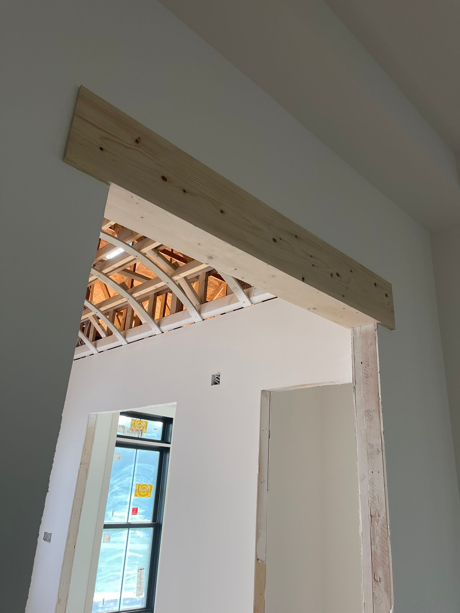 Wooden header installed above an interior doorway, unfinished drywall, view of construction.