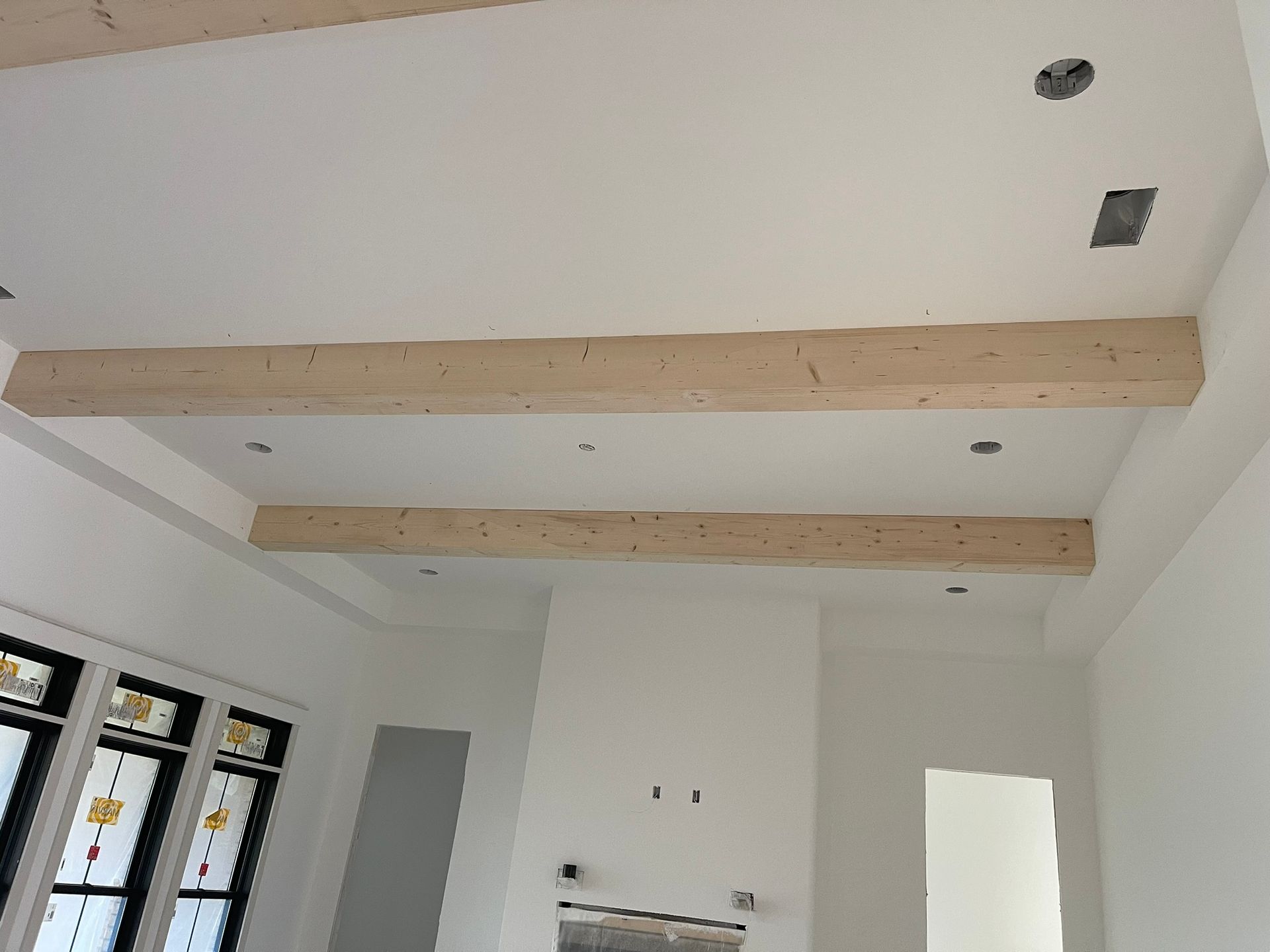 White room with recessed ceiling and two wooden beams.