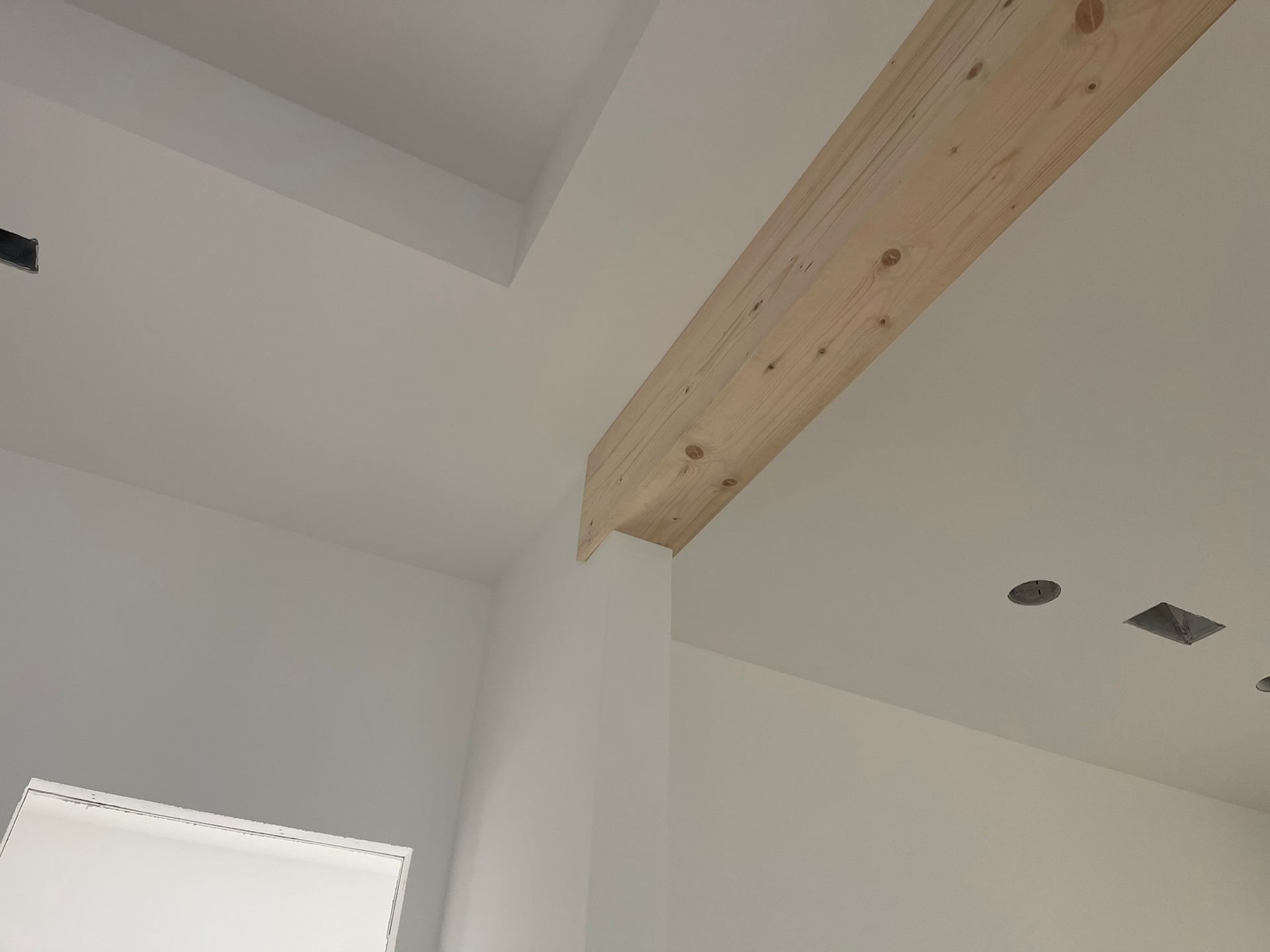White walls and ceiling with a light-colored wooden beam running across.