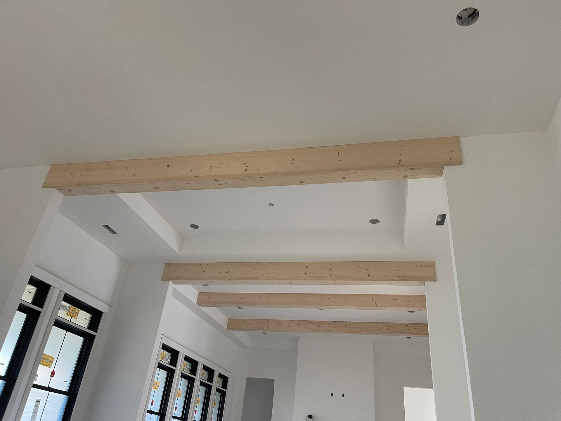 Interior view of a new construction home with light-colored wooden beams installed across the ceiling.