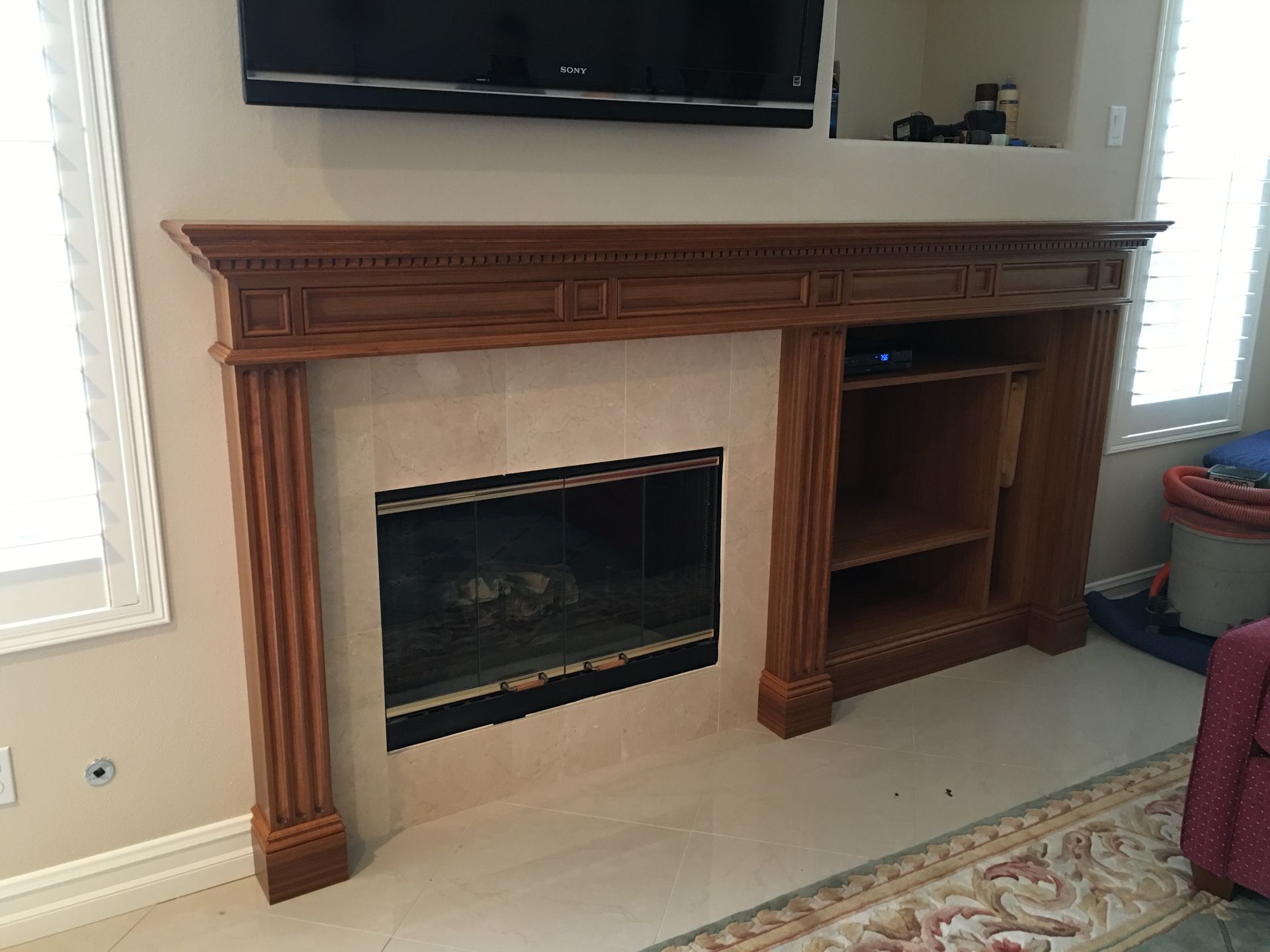 Fireplace with wooden mantel, TV above, and built-in shelving.