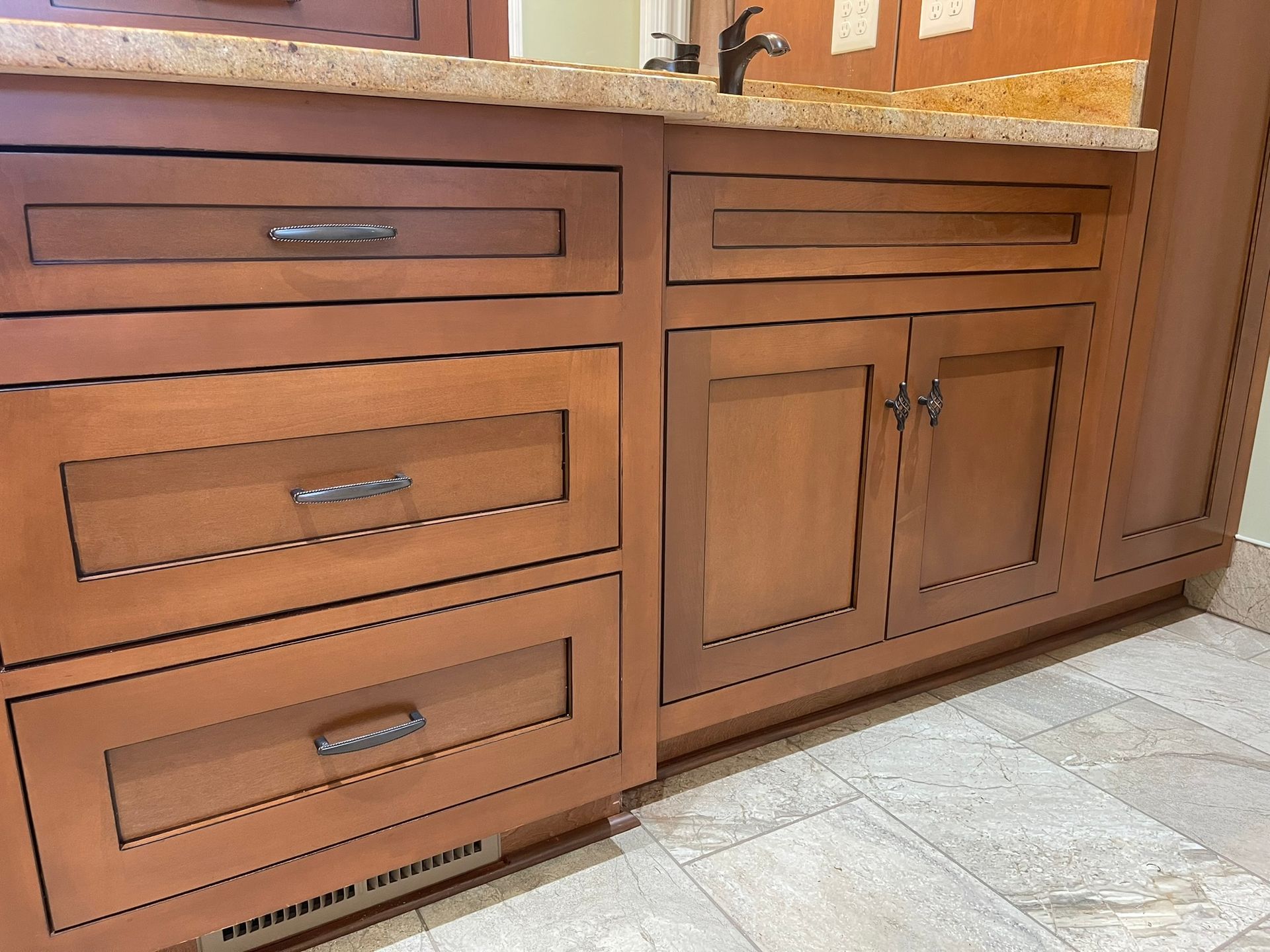 Bathroom vanity with wood cabinets, drawers, and granite countertop.