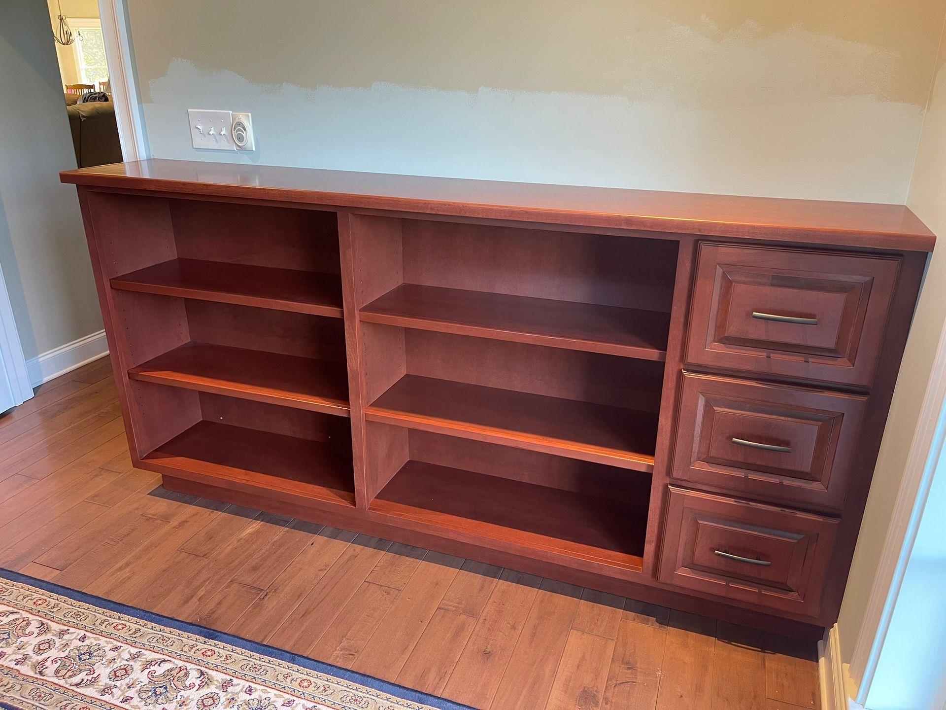 Wooden cabinet with shelves and drawers on a wood floor against a wall.