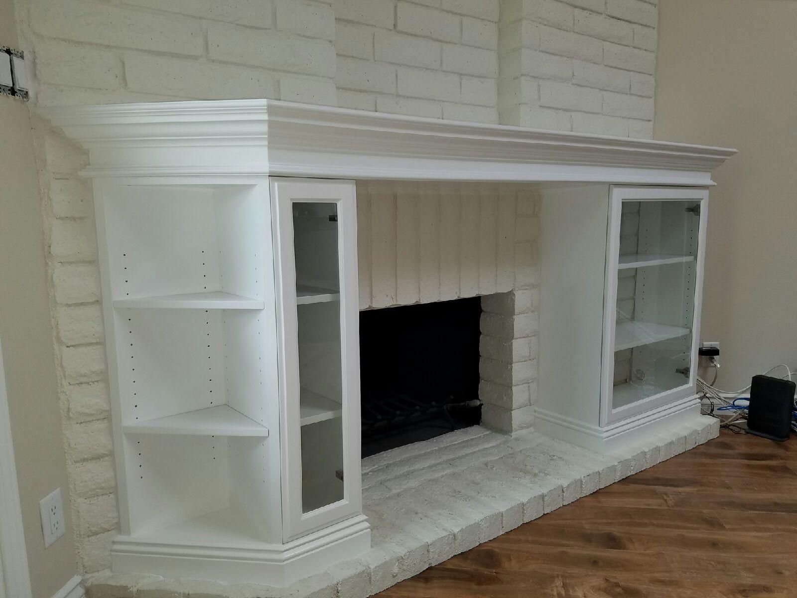 White brick fireplace with built-in bookshelves and glass-door cabinets, white painted mantel.