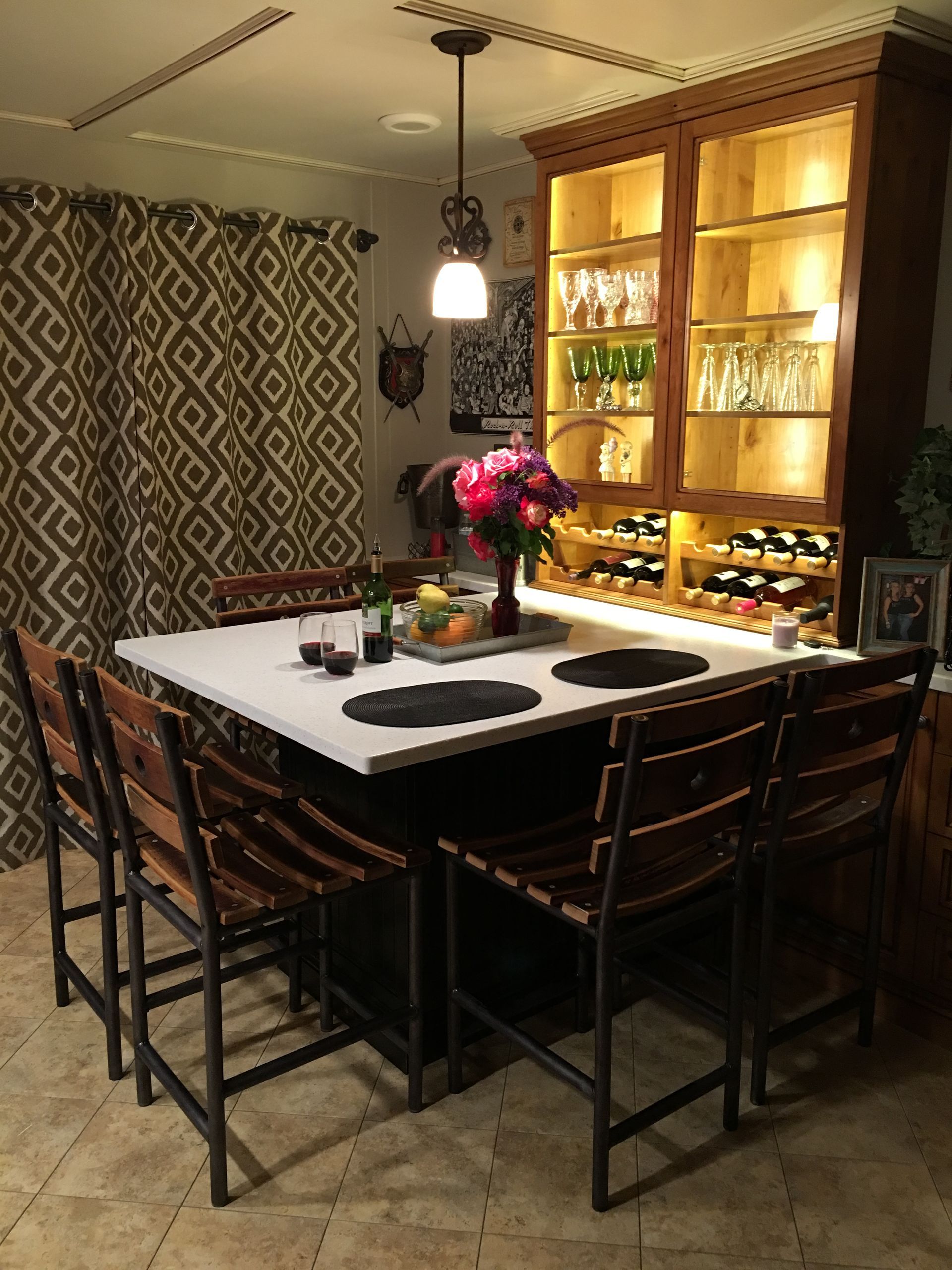 A kitchen island with seating, built-in wine storage, and a lit cabinet holding glassware.