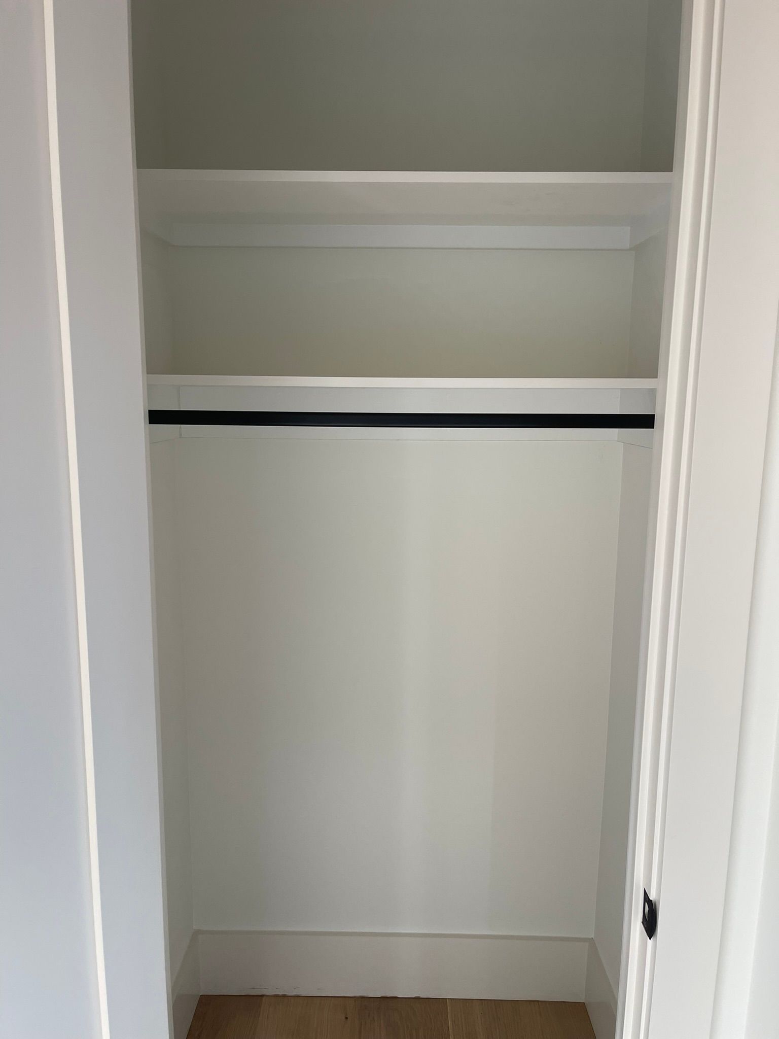 Empty white closet with a rod and two shelves.