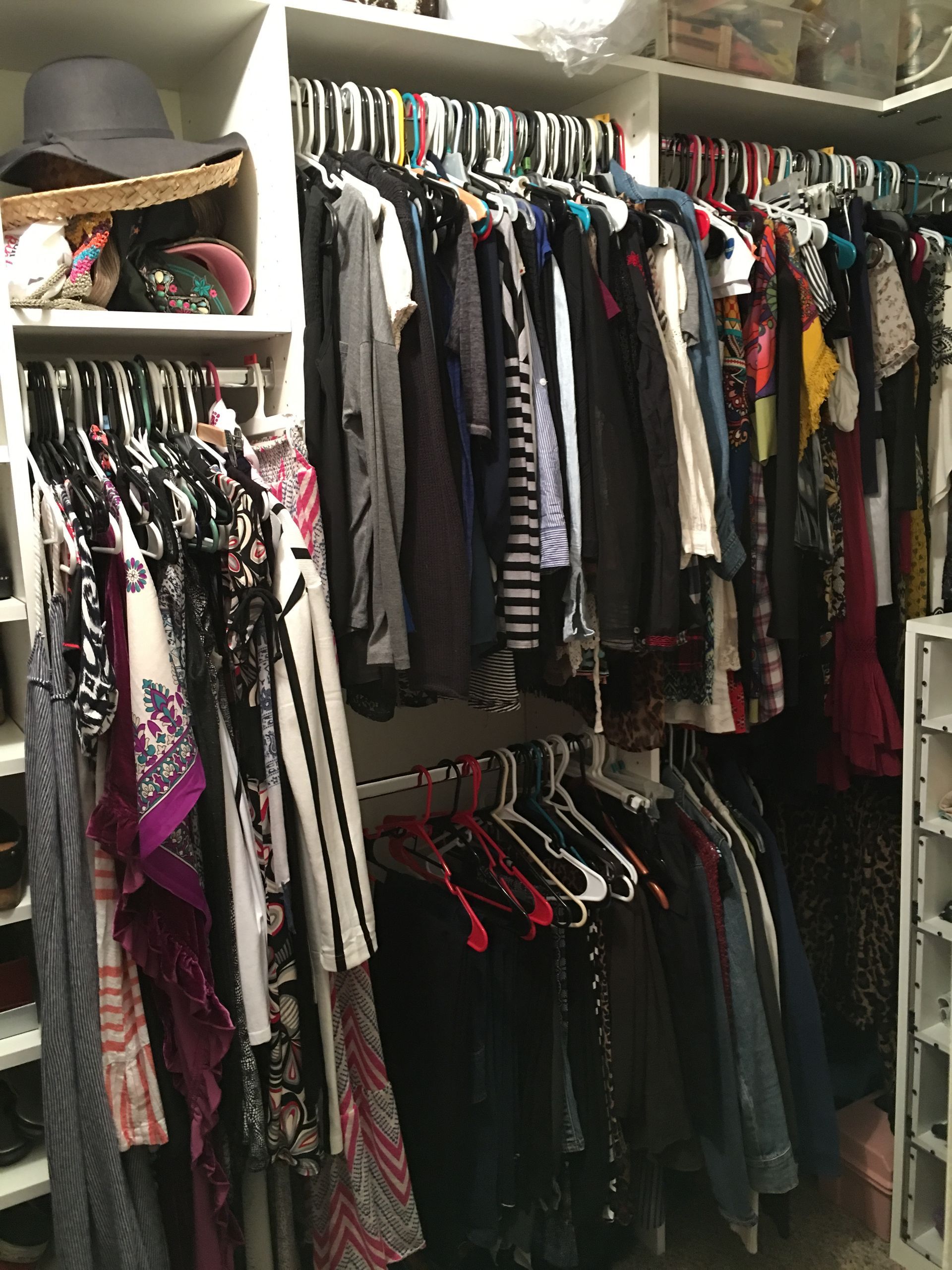 Clothes hanging in a well-organized walk-in closet. Assorted colors and styles.