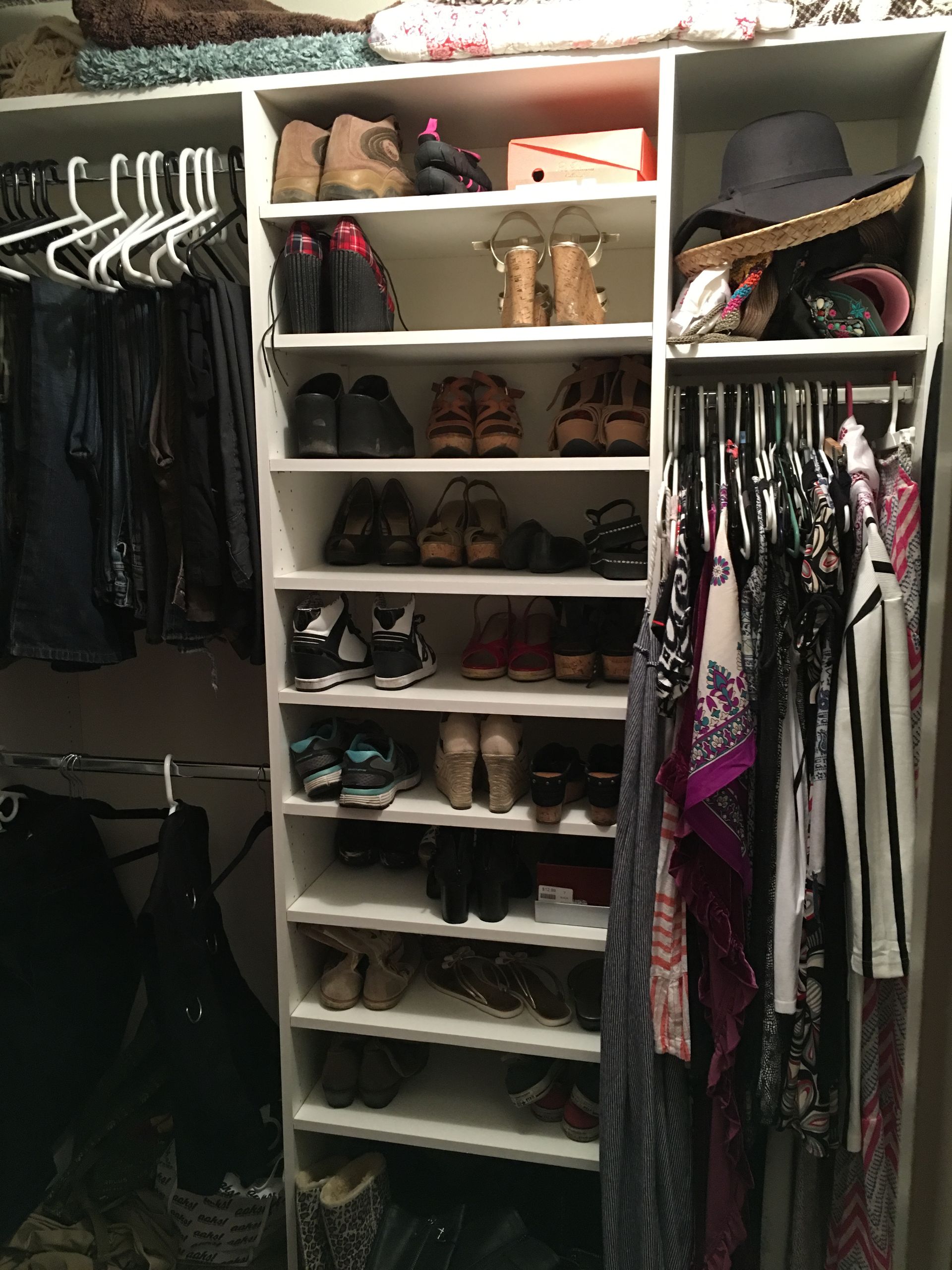 A closet with hanging clothes, shoe shelves, and a hat rack.