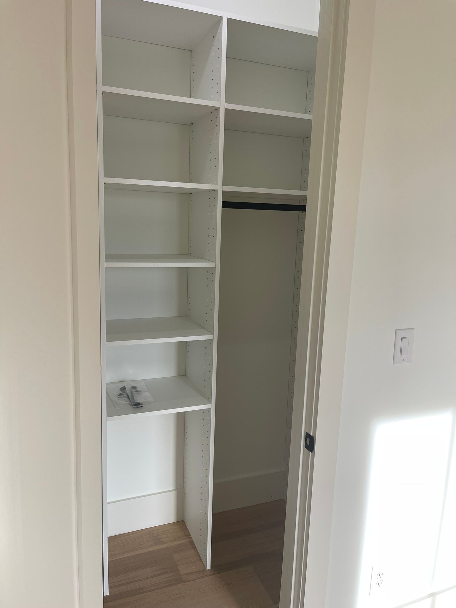 White closet interior with shelves on one side and hanging rod on the other.