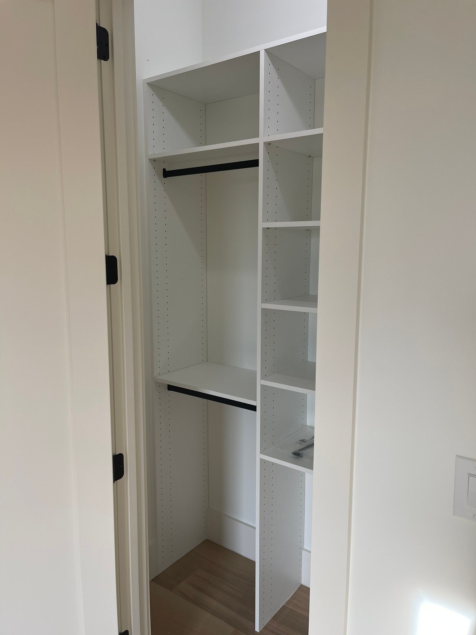 White closet with shelves and hanging rods inside a doorway.